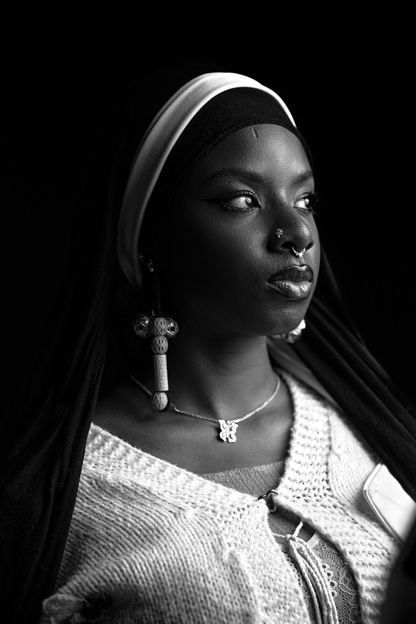 Dramatic black and white portrait series showing a person in a white sweater with jewelry against a dark background.
