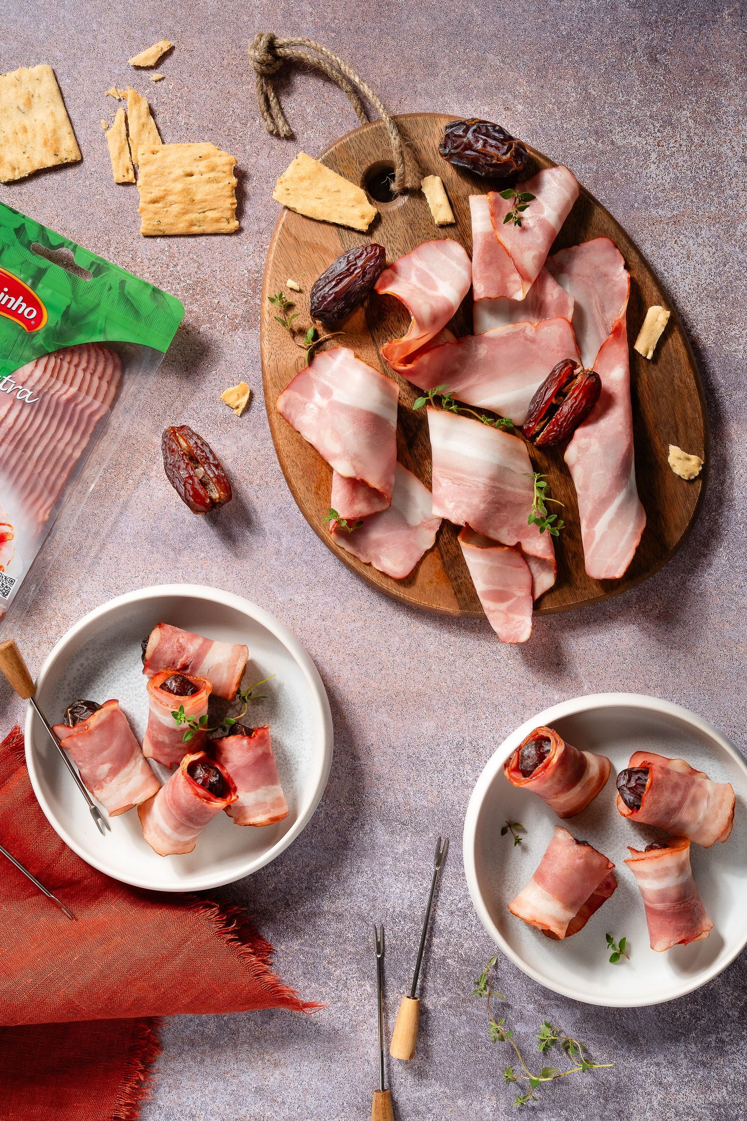 Rolled meat appetizers with dates arranged on white plates and wooden board.