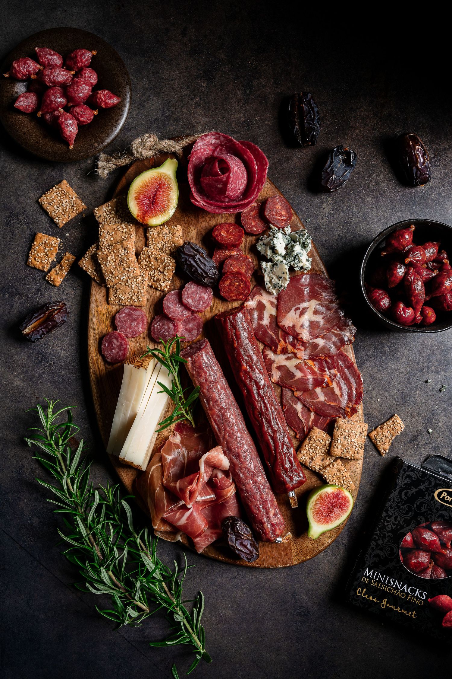 Dark moody charcuterie board with cured meats, figs, and berries on black background.