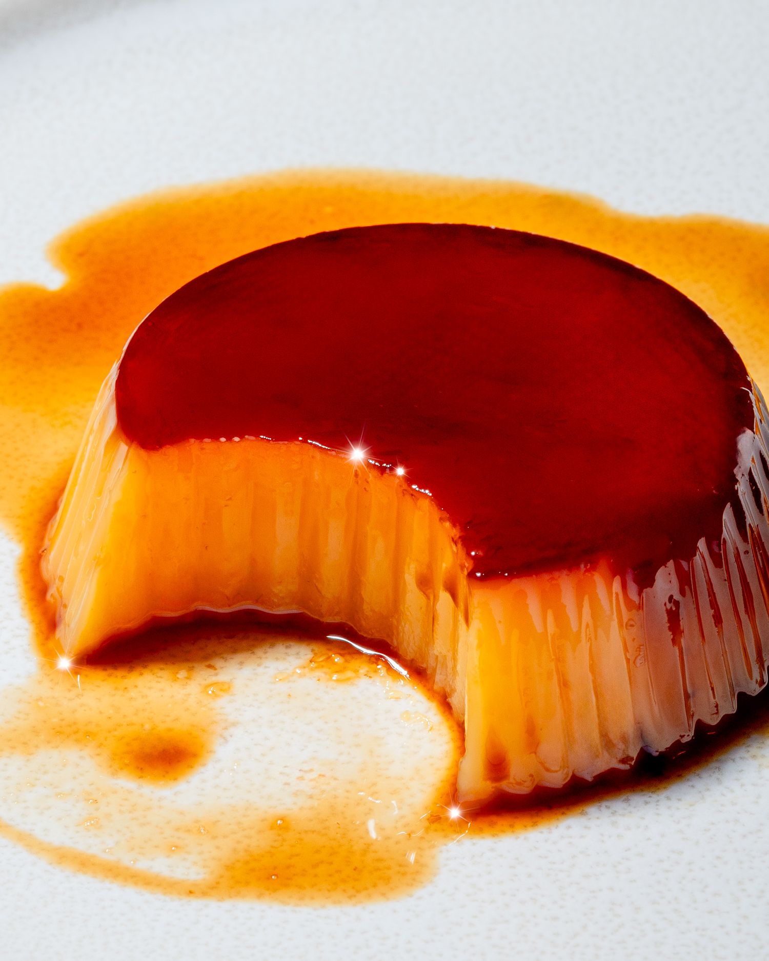 A row of pudding-covered caramel arranged in a gradient pattern against a white background.