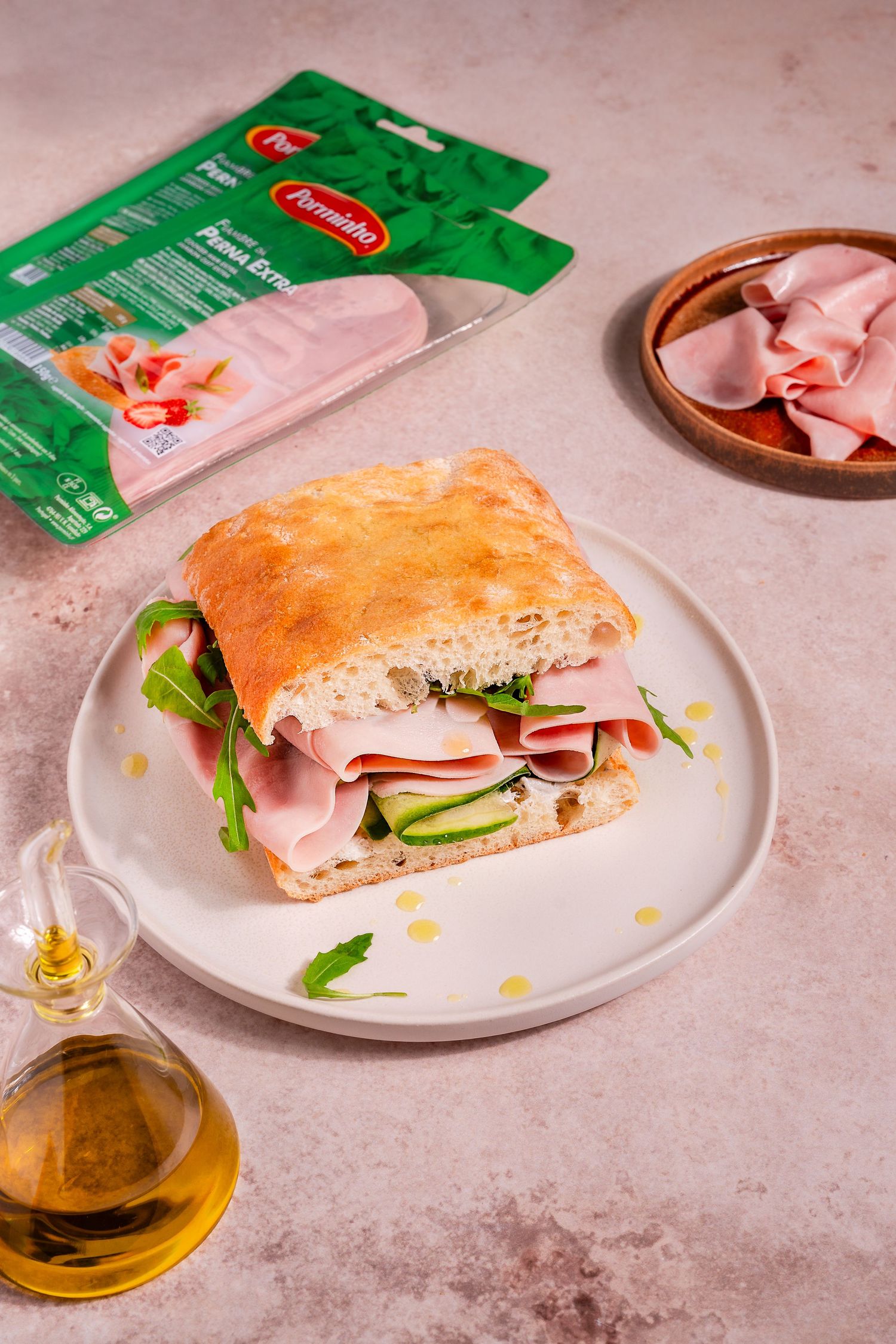 Italian sandwich with ham and vegetables on white plate with olive oil.