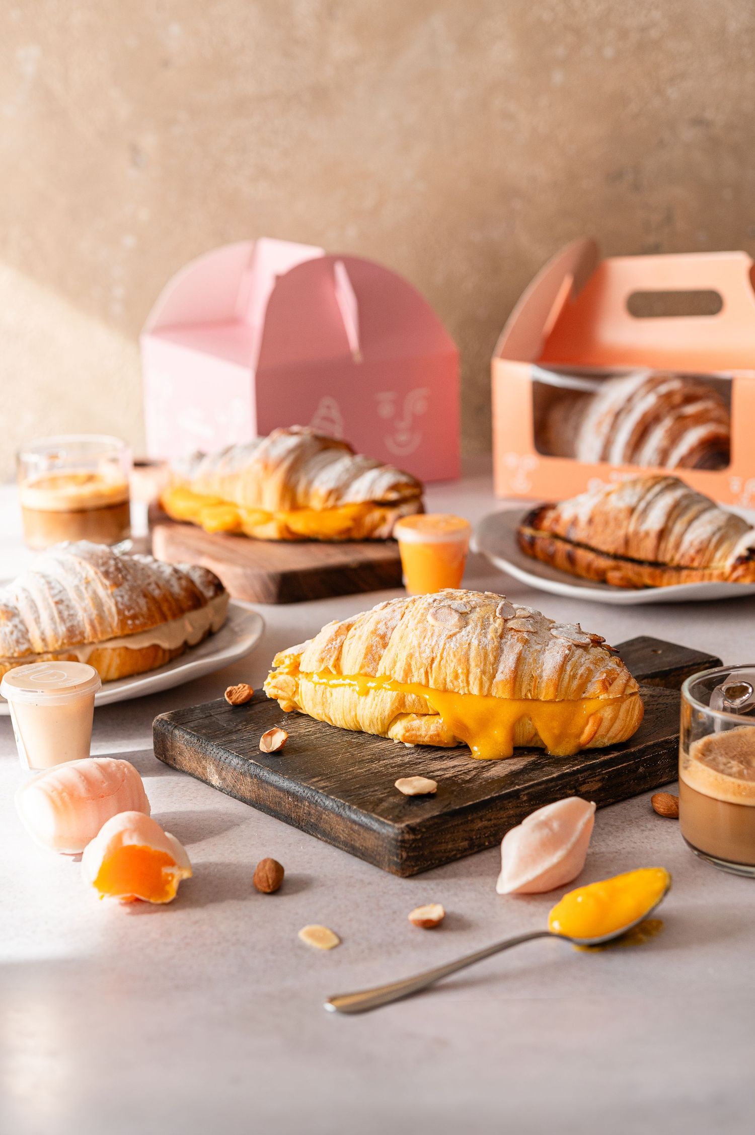 Fresh croissants and pastries arranged on wooden boards with scattered nuts and citrus fruits.