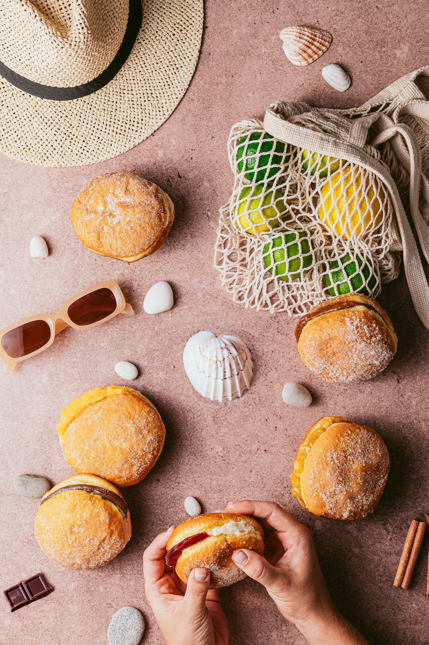 Fresh citrus fruits in mesh bags being arranged on textured surface with chocolate and cinnamon.