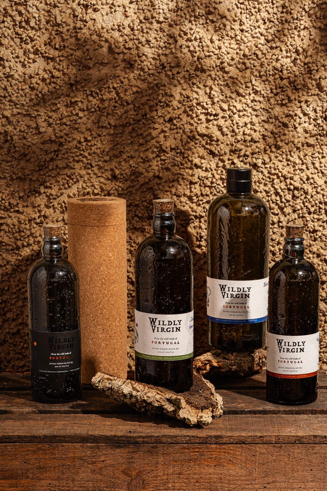 Dark glass olive oil bottles arranged in a rustic cellar setting with textured stone wall background.