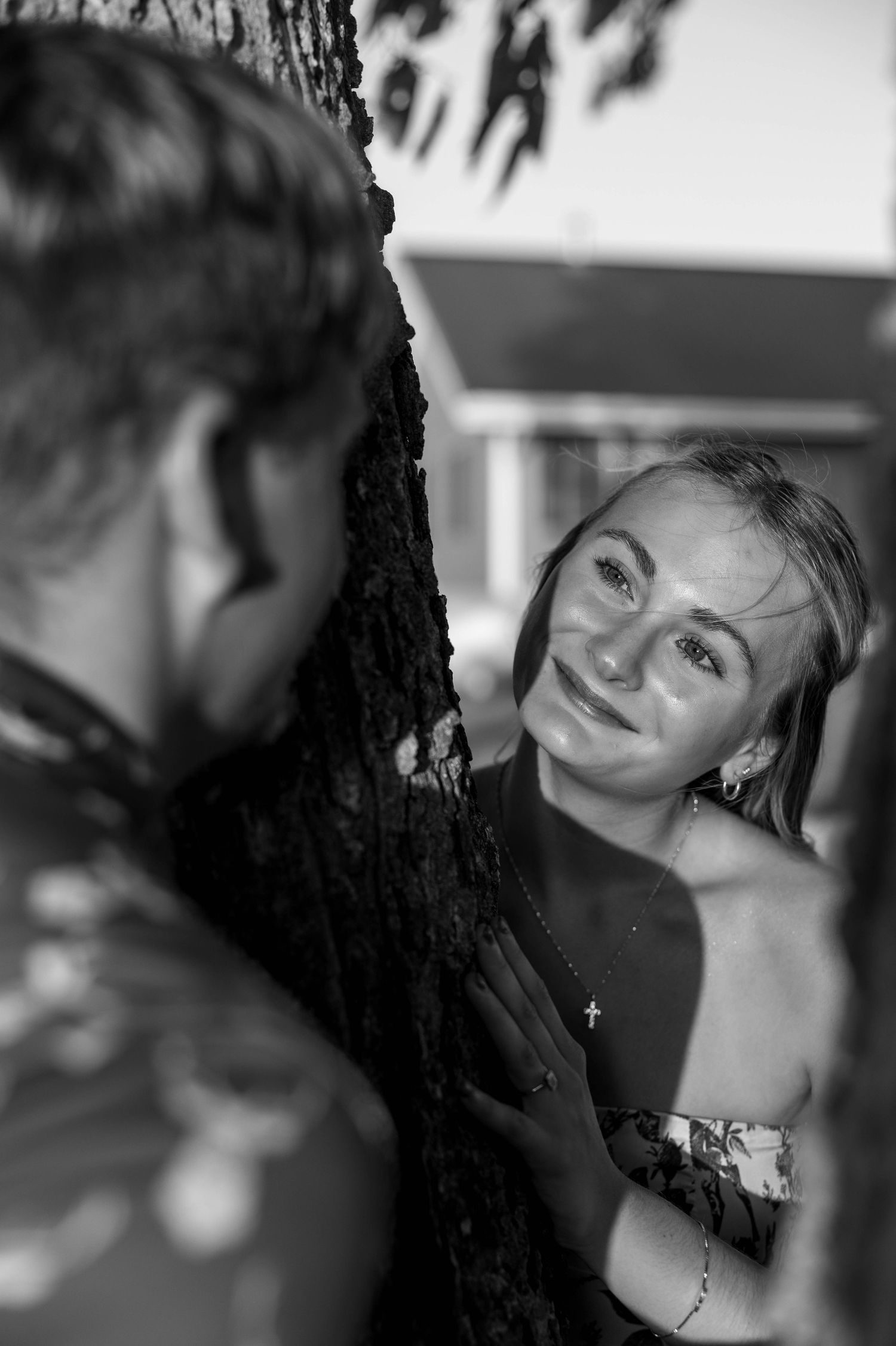A girl looking around a tree at a guy.