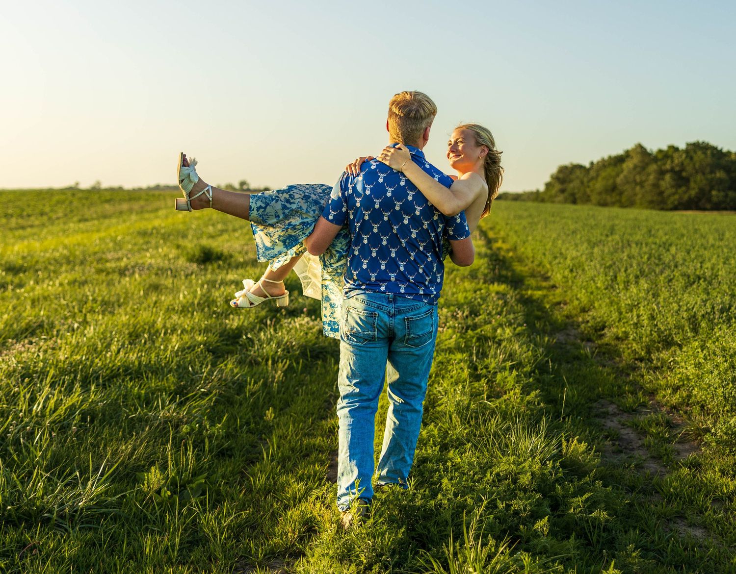 A guy carrying a girl, walking in a field.