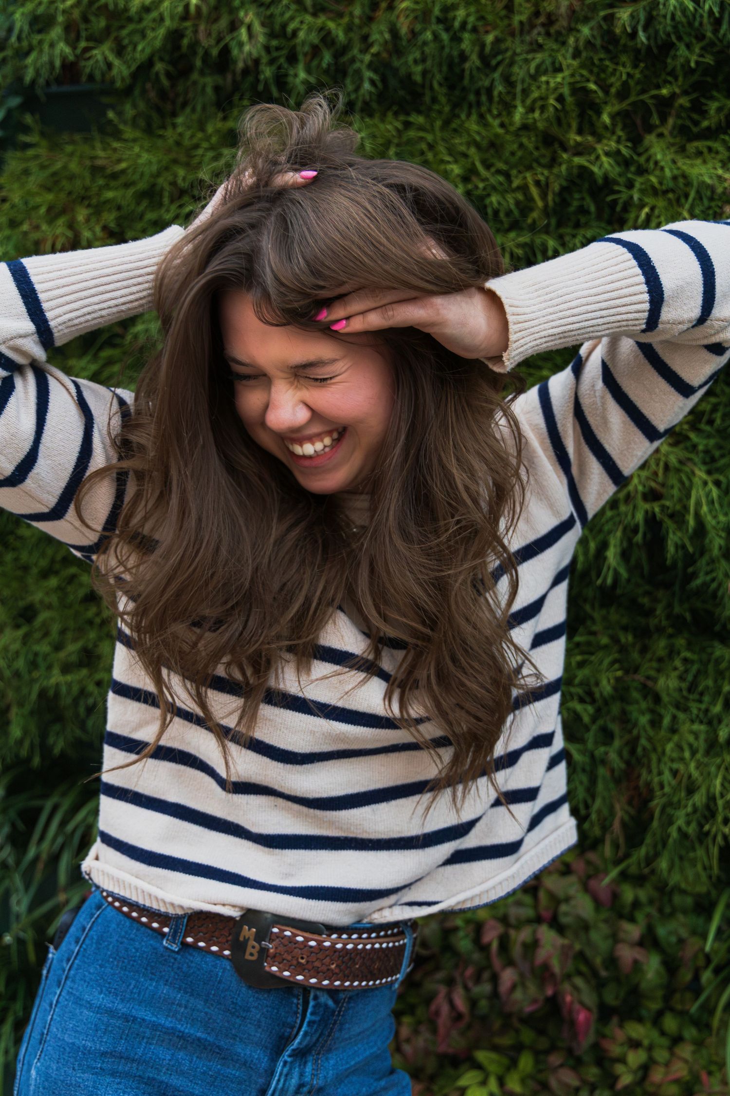 A girl smiling and playing with her hair in a crazy way.
