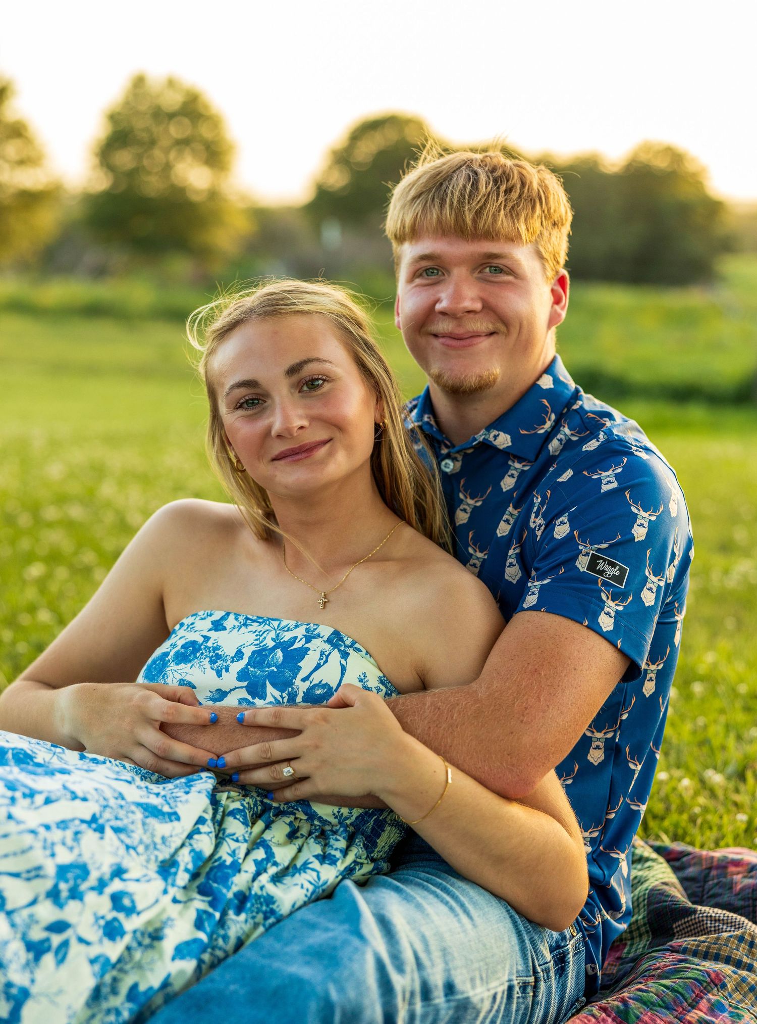 A couple sitting on the ground on a blanket.