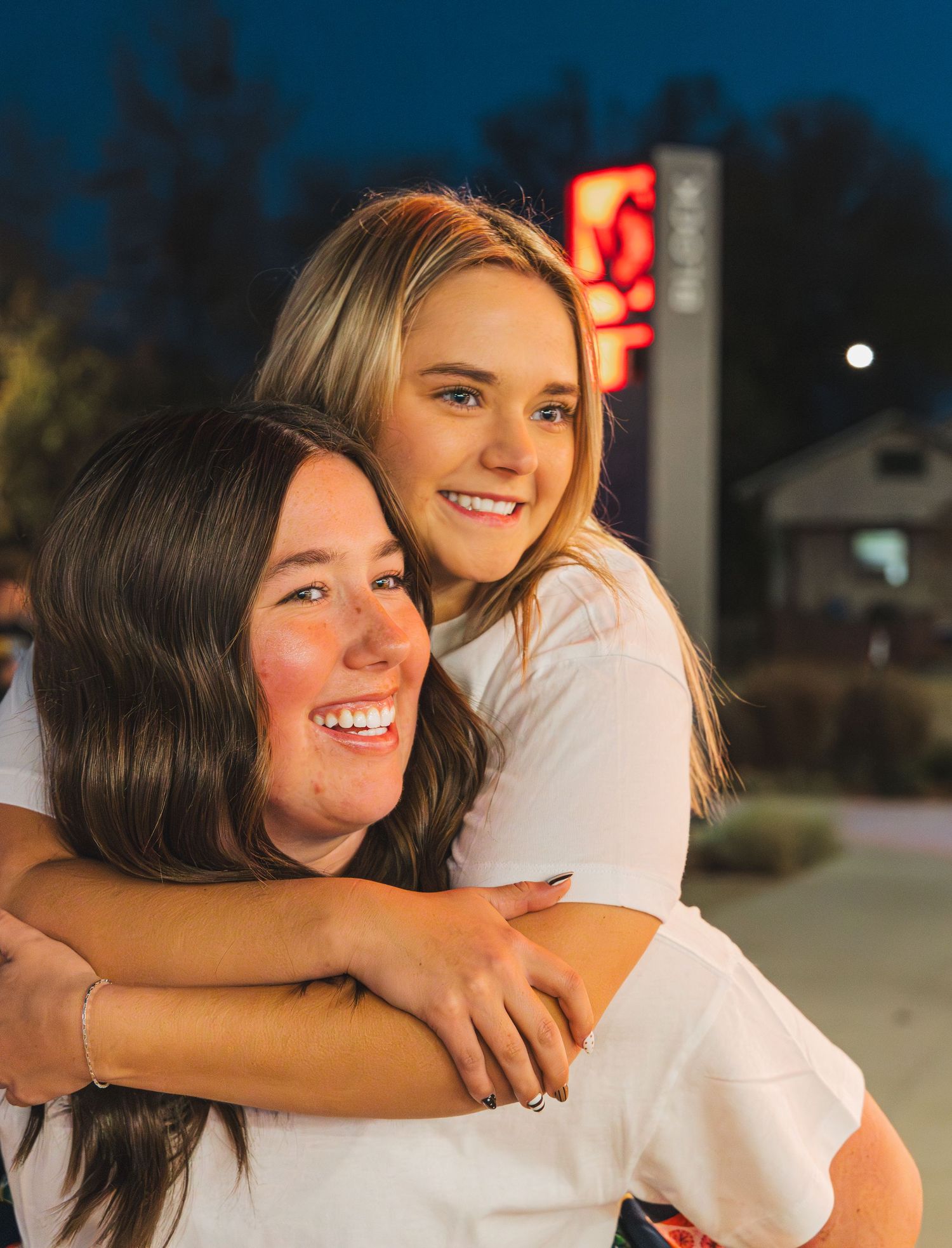 Two girls hugging and looking into the distance.
