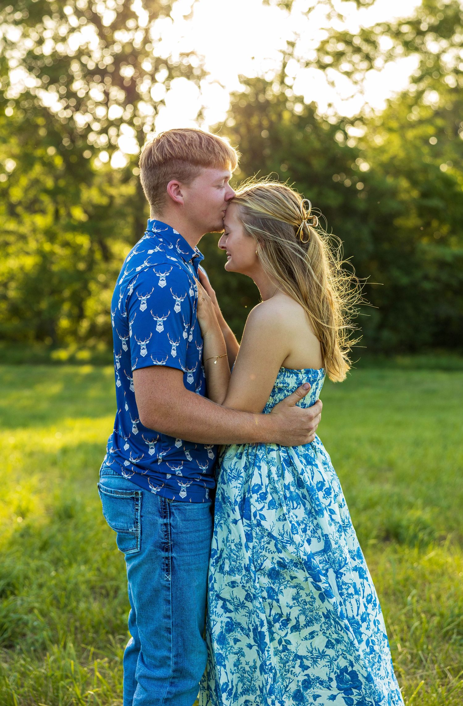 A couple hugging, with the guy kissing her forehead.