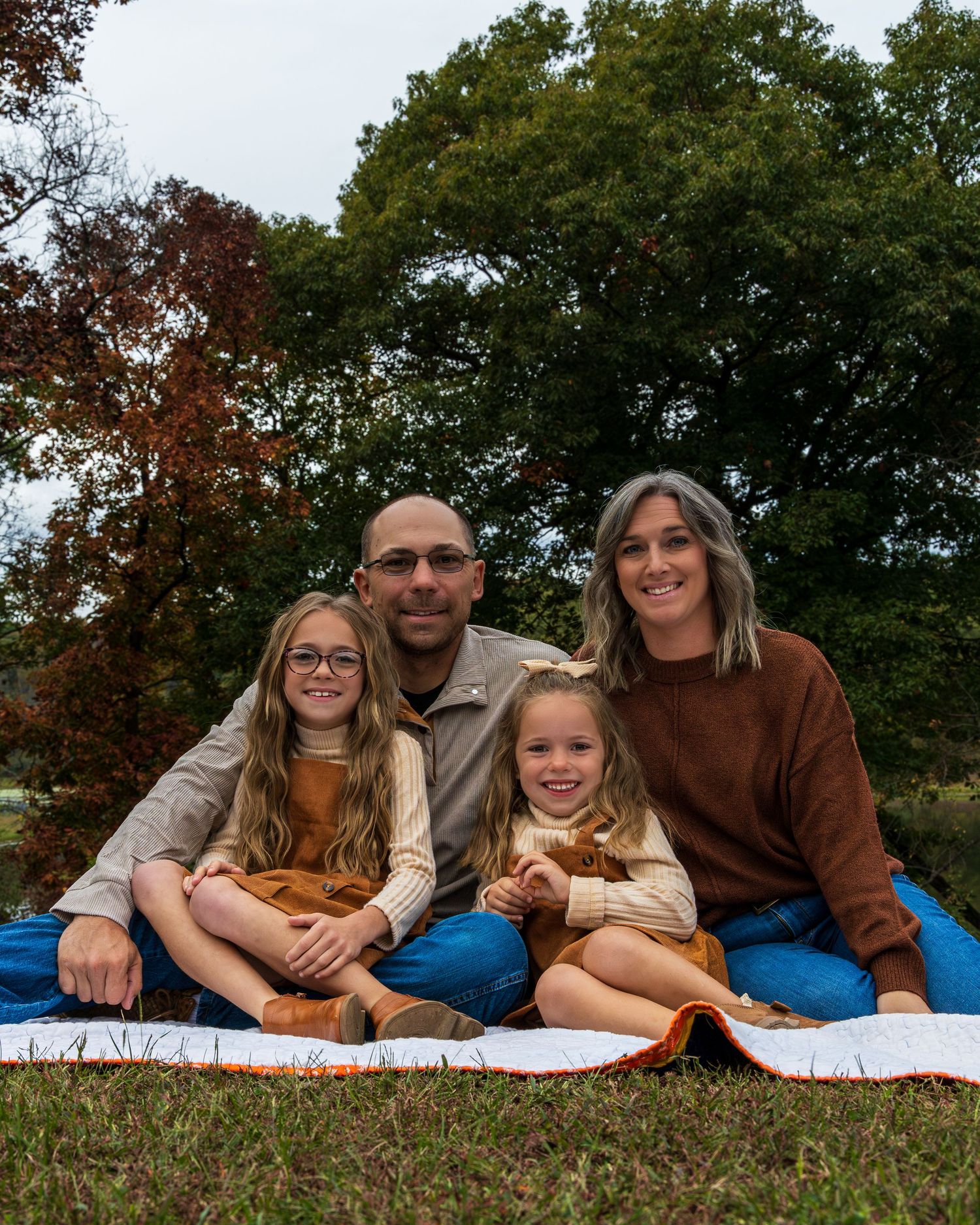 A young family sitting on a blanket.