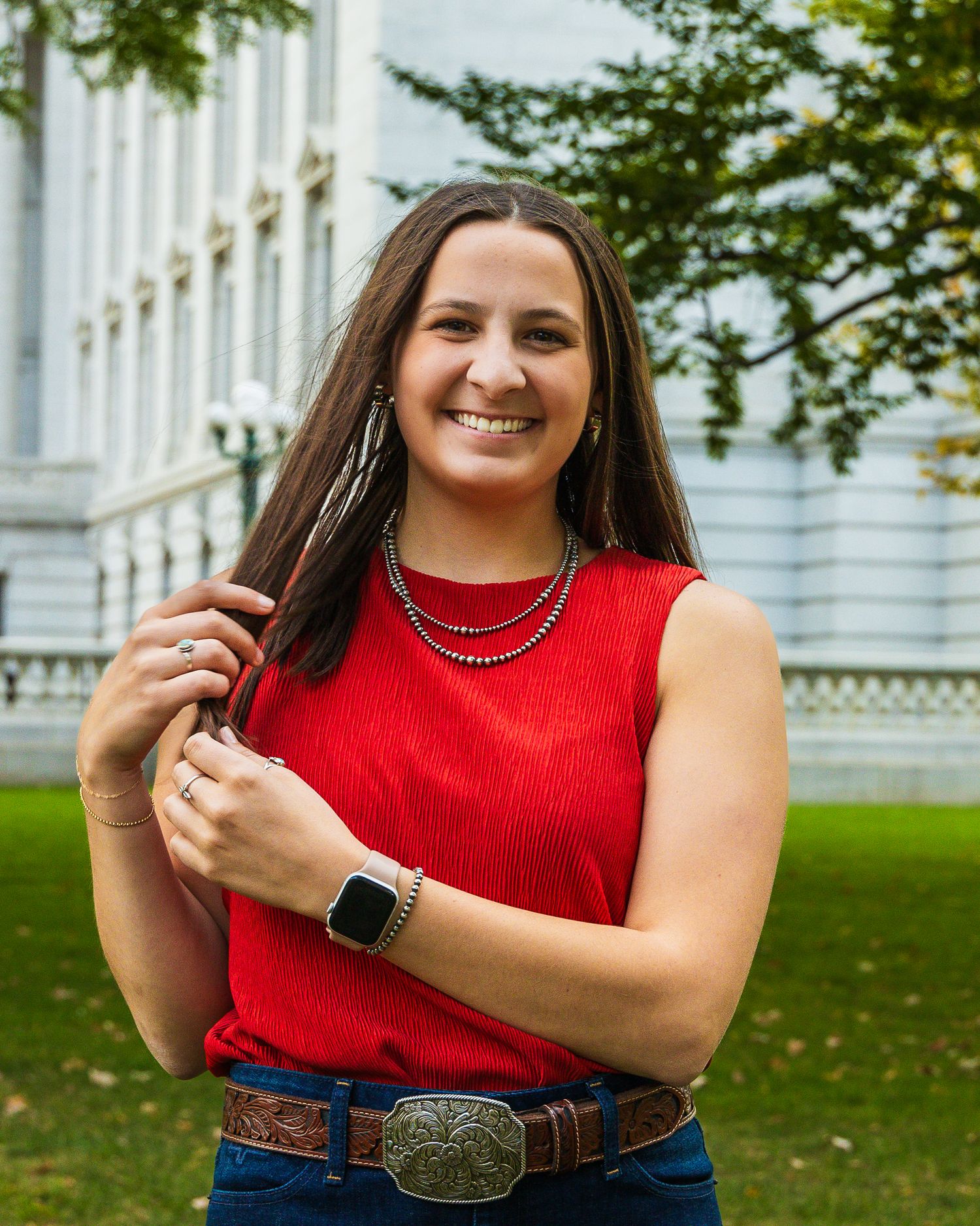 A girl standing in front of a capital building and playing with her hair.
