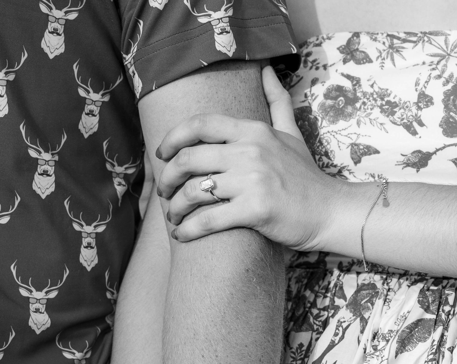 A close up of a couple holding hands, zoomed in on her ring.