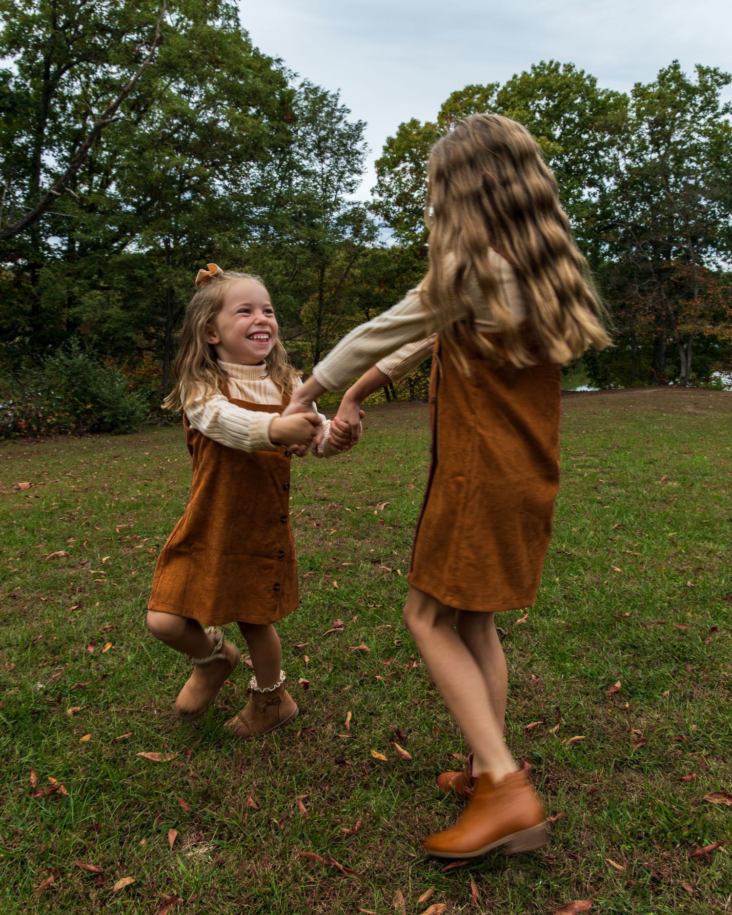 Two little girls holding hands, spinning smiling at each other.