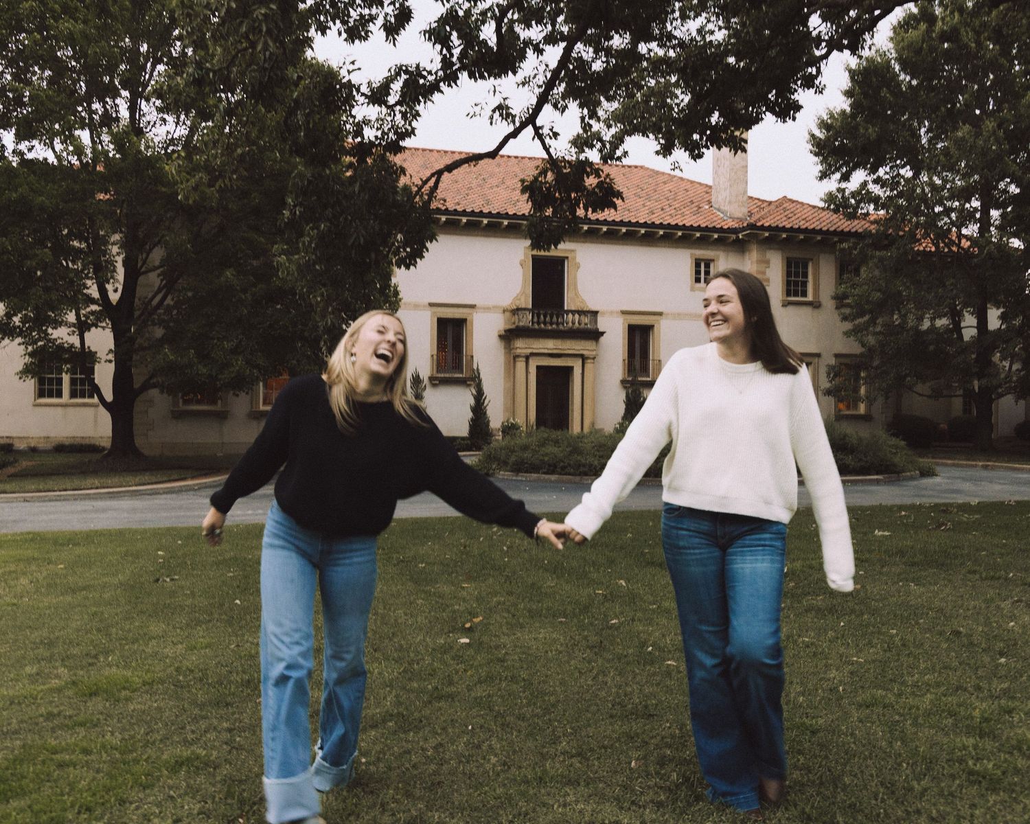 Two girls walking, holding hands in front of a museum area.