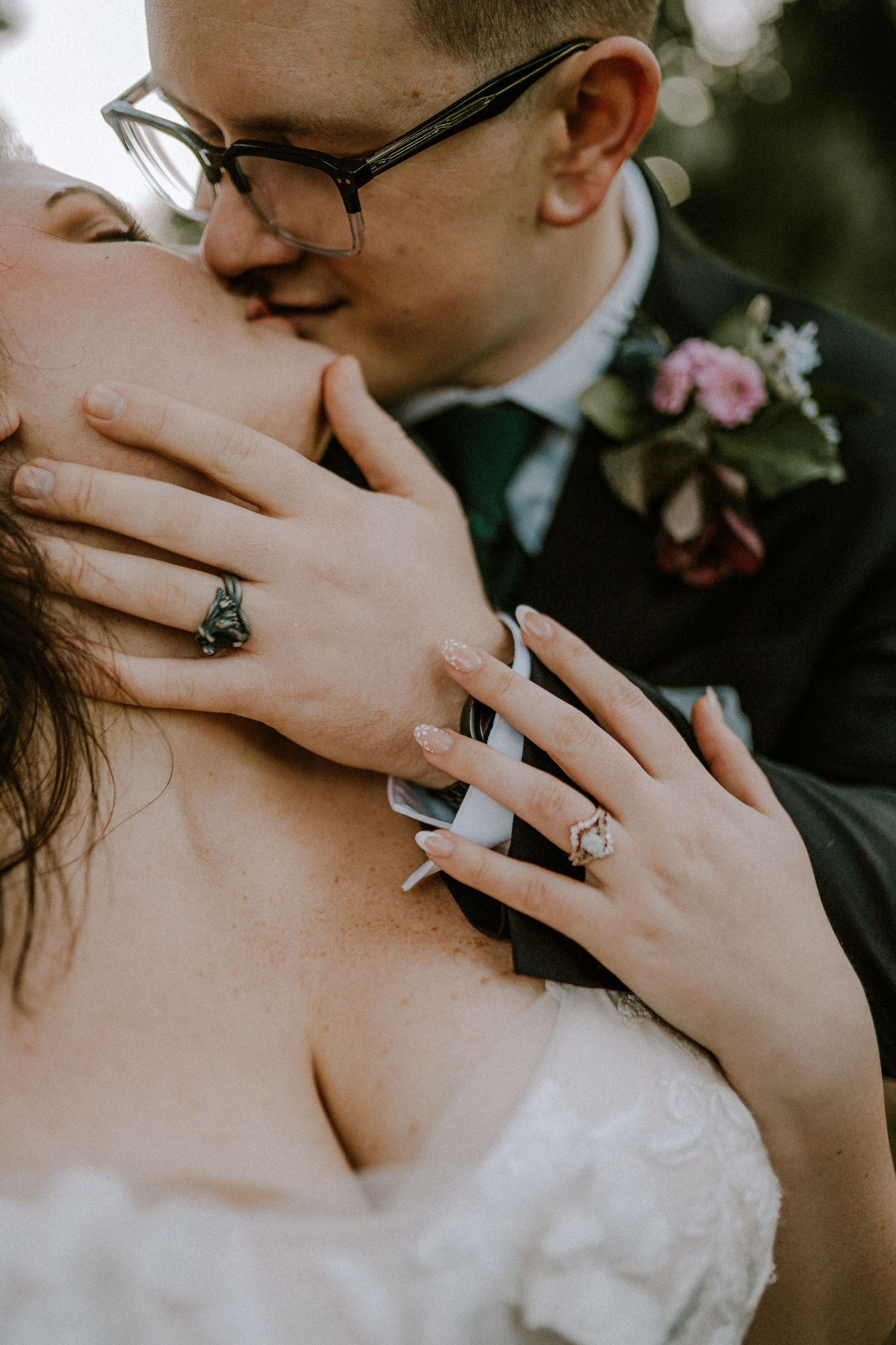 Close-up of bride and groom kissing, showcasing elegant engagement ring and wedding band on bride's hand.