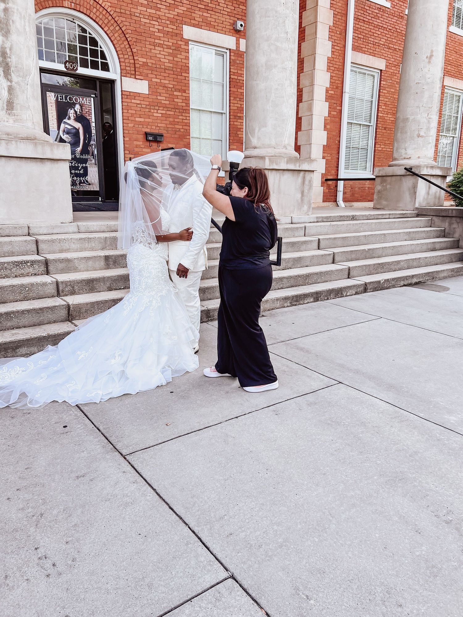 behind the scene's of a photographer taking a photo of bride and groom under vail