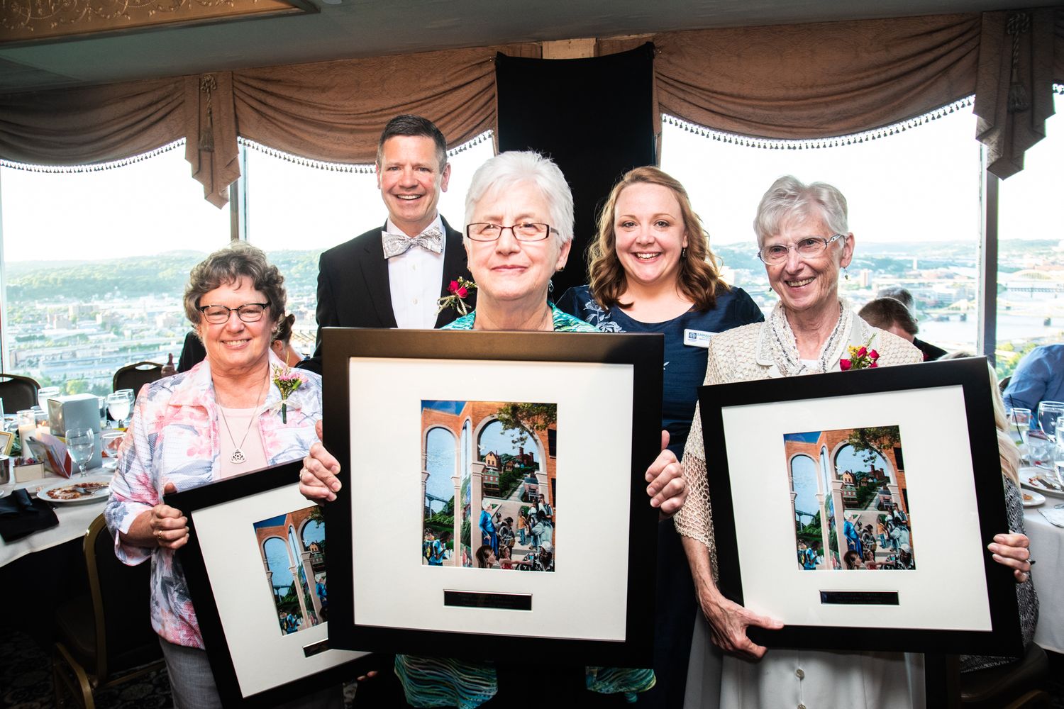 Five people proudly holding framed awards at a formal ceremony dinner event.