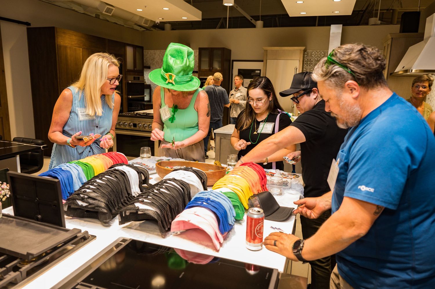 People browsing colorful hats at an indoor event, with one guest wearing a green St. Patrick’s Day hat.