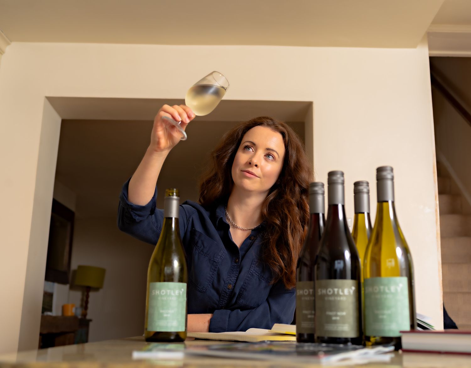 Commercial portrait of vineyard owner Charlotte Davitt-Mills swirling and examining a glass of this season's wine, Shotley, Suffolk.