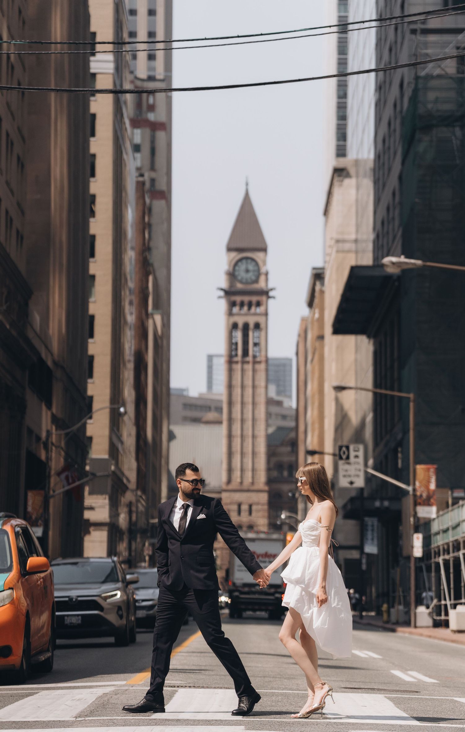A romantic urban wedding photo session with an elegant white dress against city architecture and clock tower.