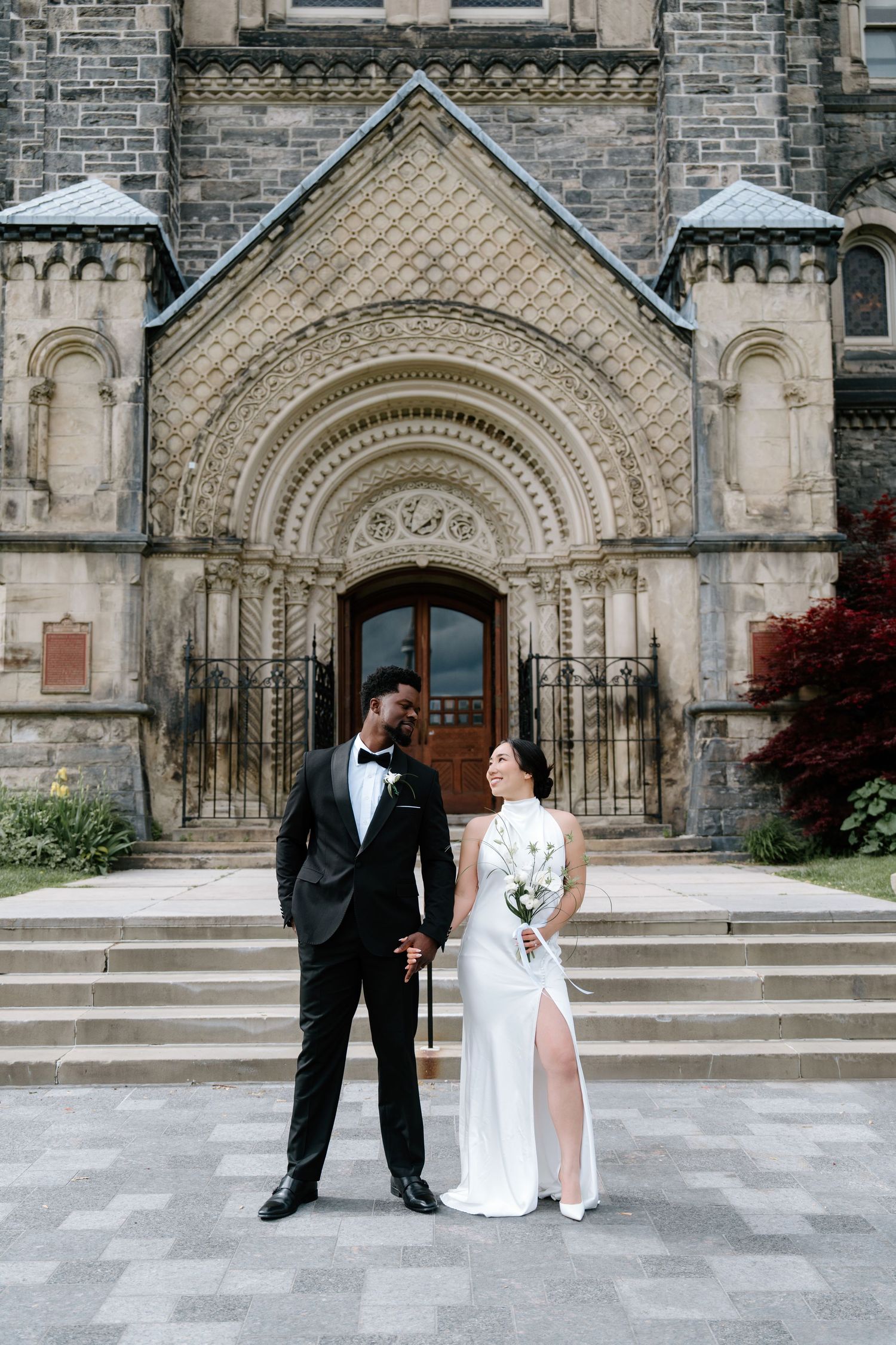 Ornate Gothic church entrance with stone archways provides elegant backdrop for wedding portraits.