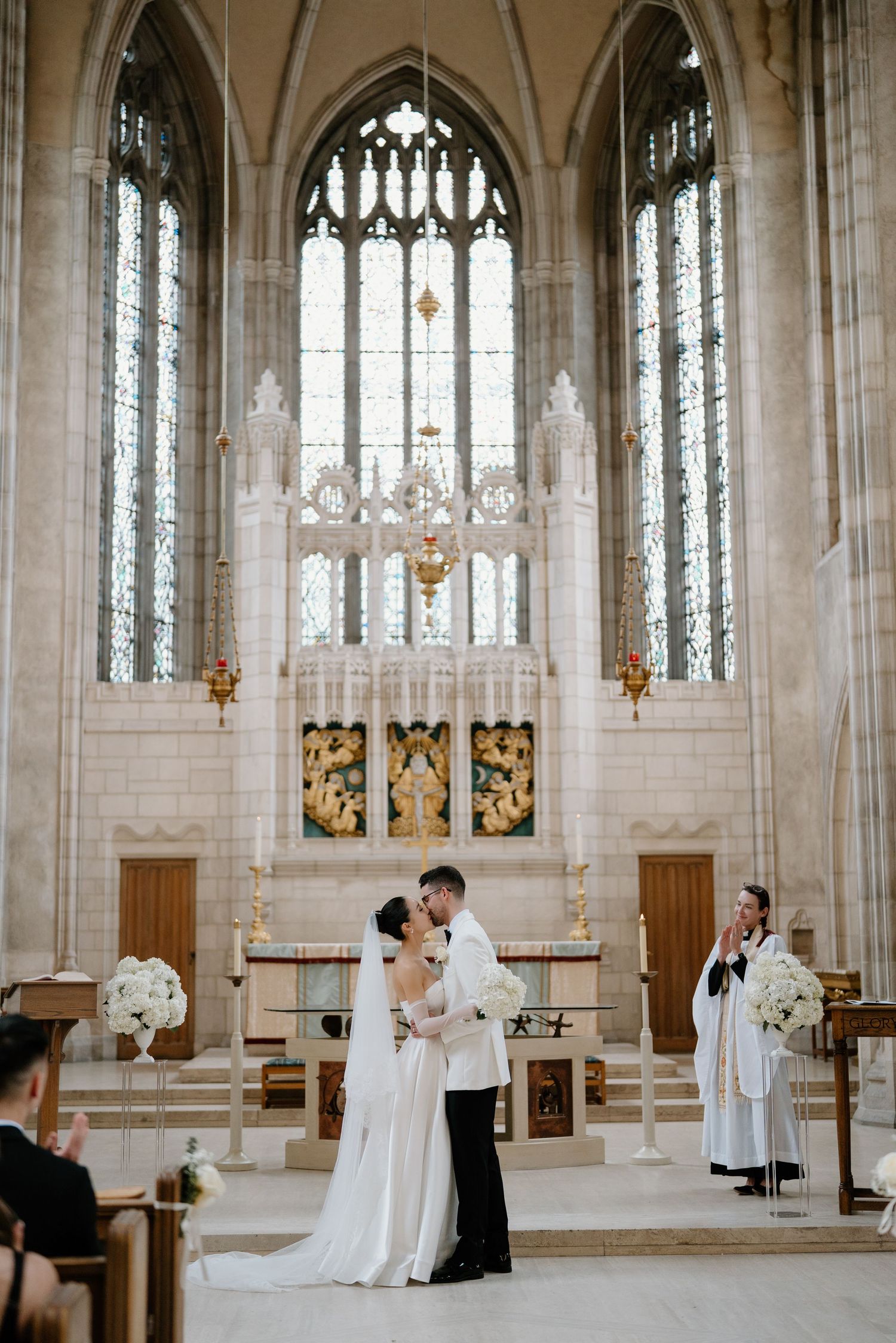 A wedding ceremony in a gothic church with stained glass windows and vaulted ceilings.