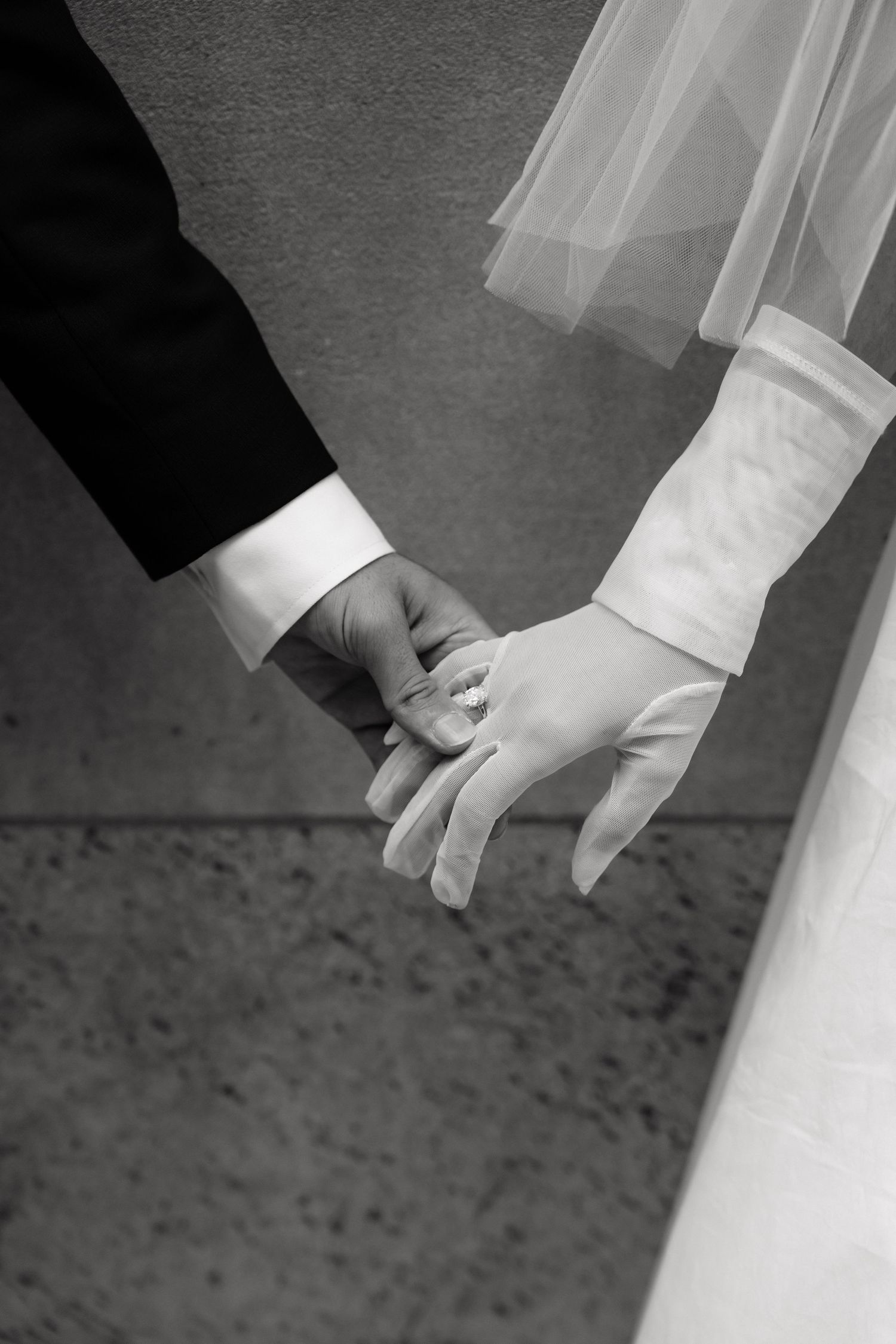 A series of black and white close-up shots showing wedding couple's hands holding each other in sequence.