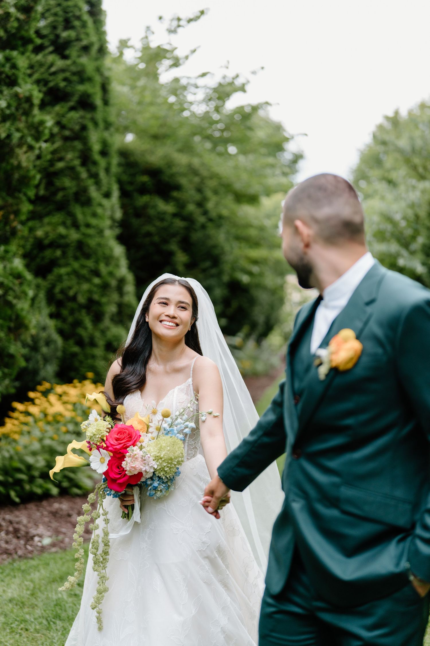 A joyful outdoor wedding moment captured in a garden setting with colorful flowers and greenery.
