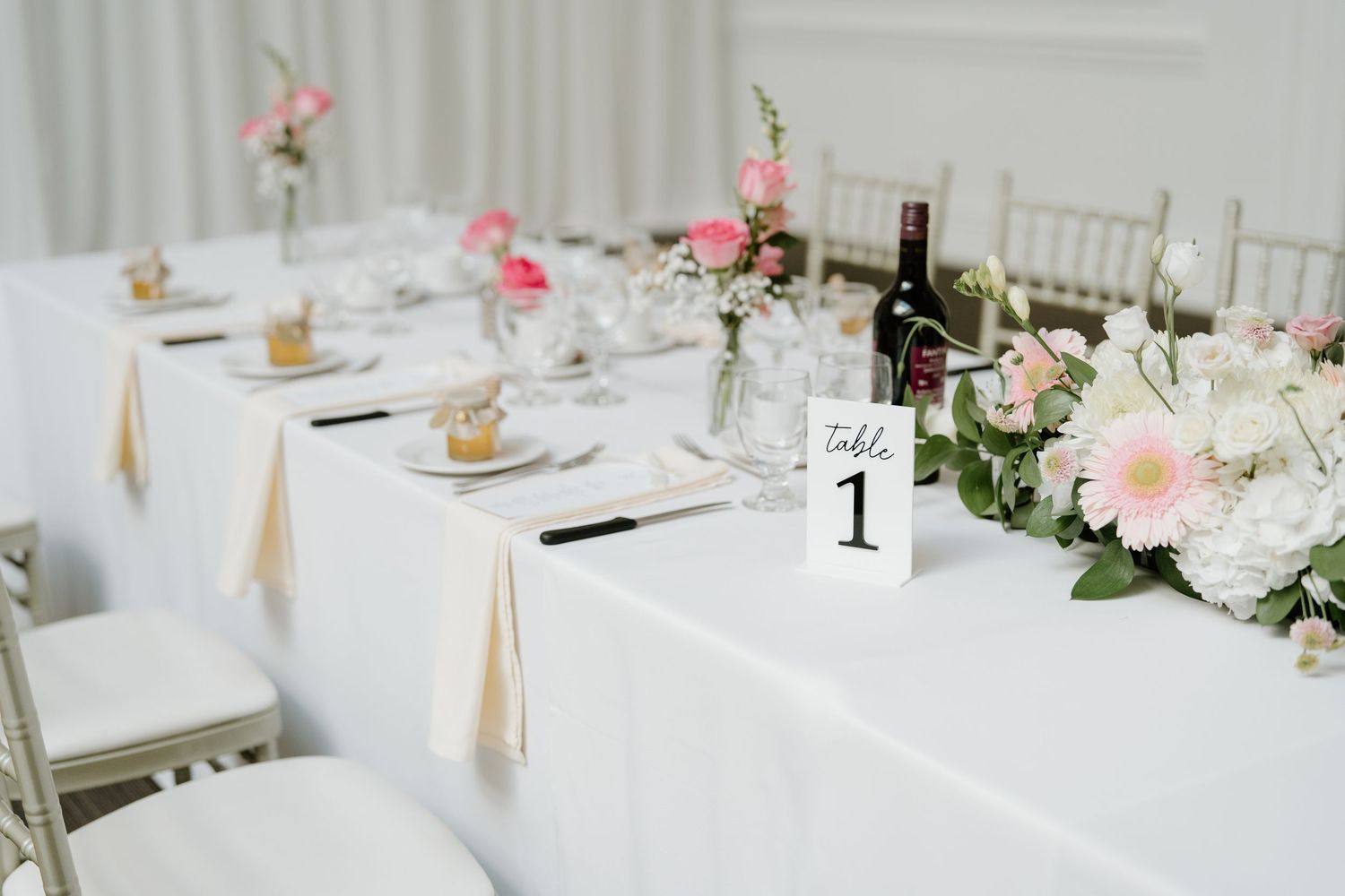 Elegant white wedding reception tables decorated with pink and blush floral centerpieces and tapered candles.