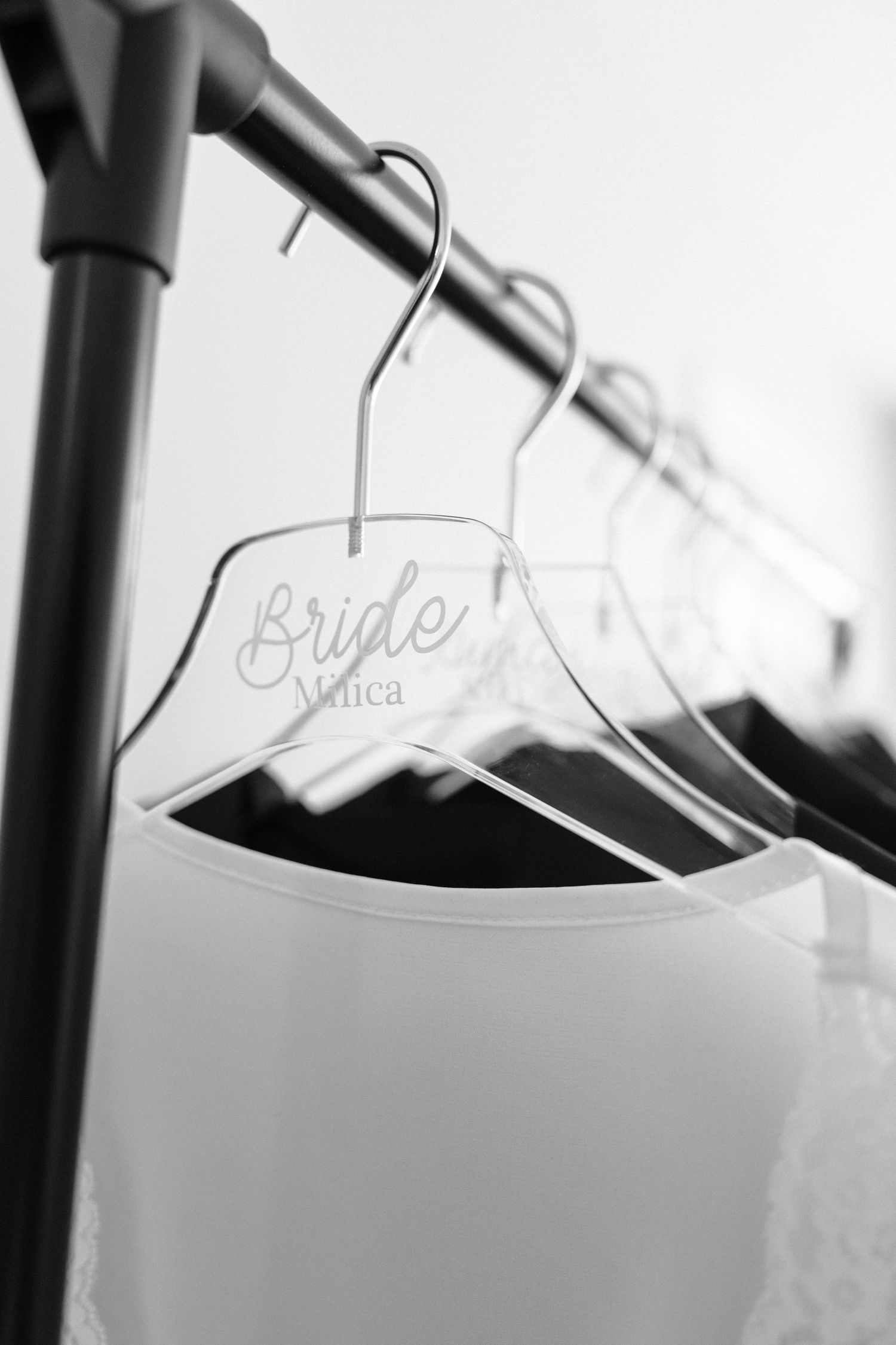 Wedding dress hangers with personalized name labels shown in black and white photography.