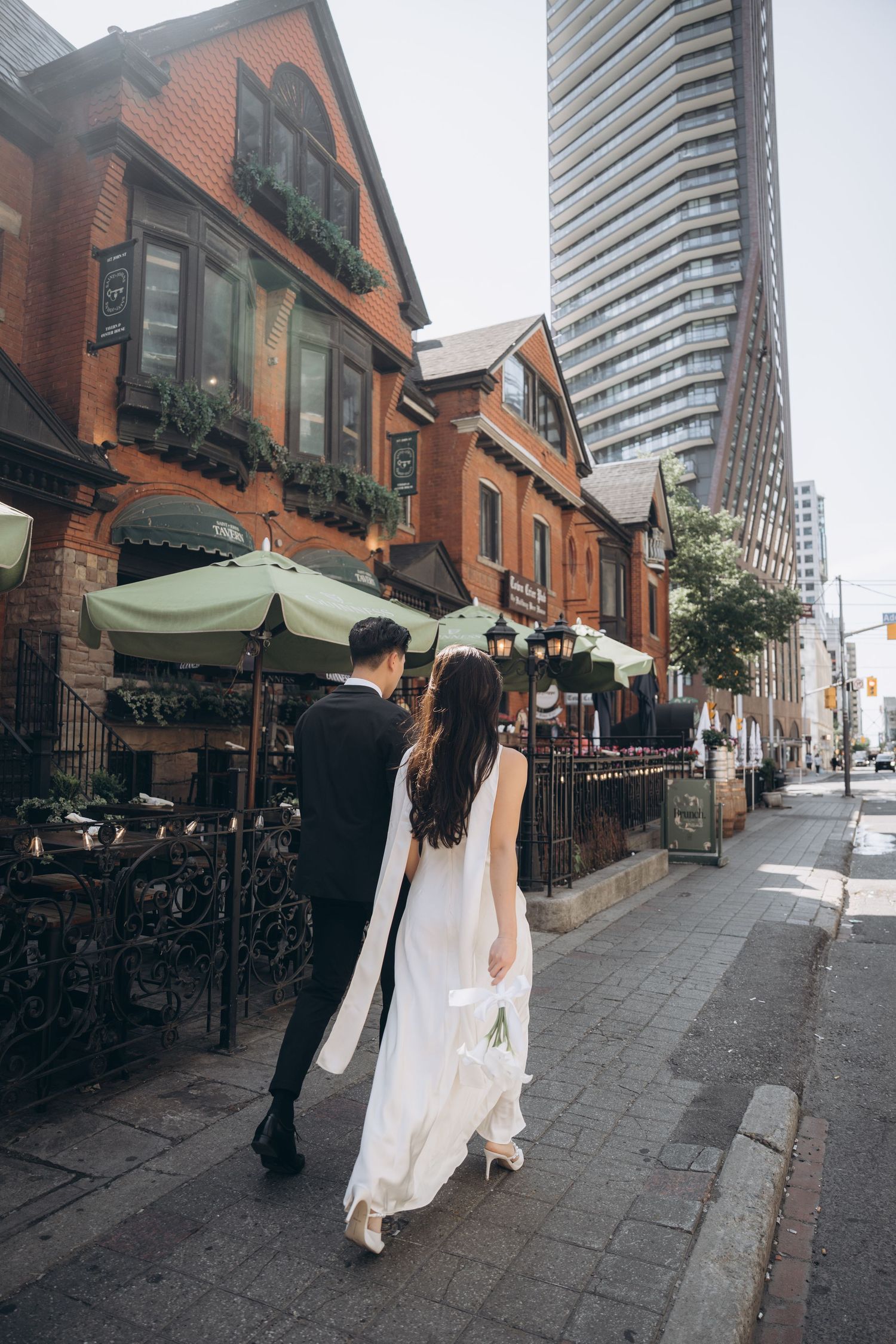 A sequence of candid street photography showing a couple walking past historic brick buildings and storefronts in an urban setting.
