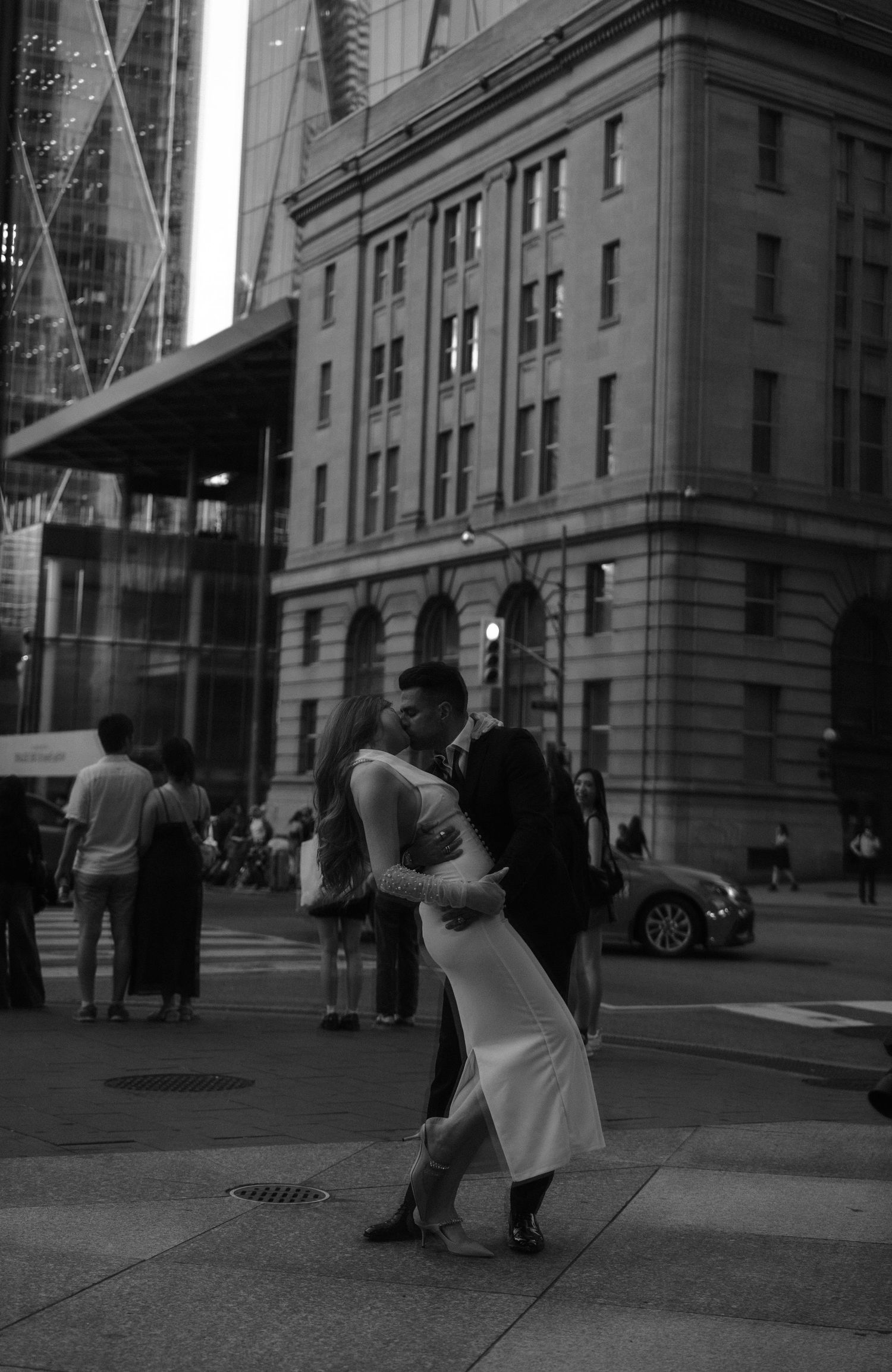 Street scene in black and white showing multiple figures in motion across a city sidewalk near a grand building.