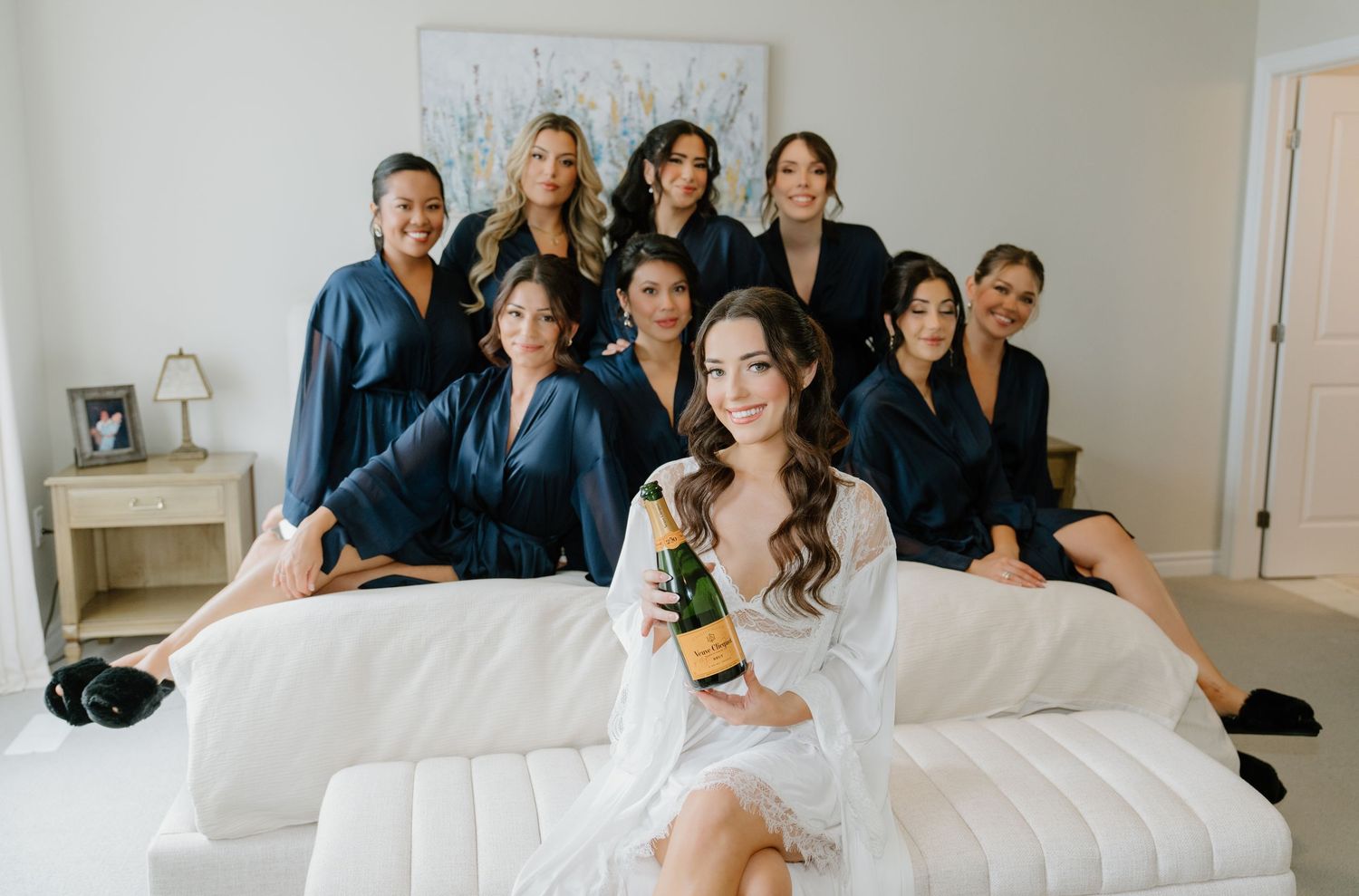 A group wearing matching navy blue robes relaxes together on a white couch during a special occasion.