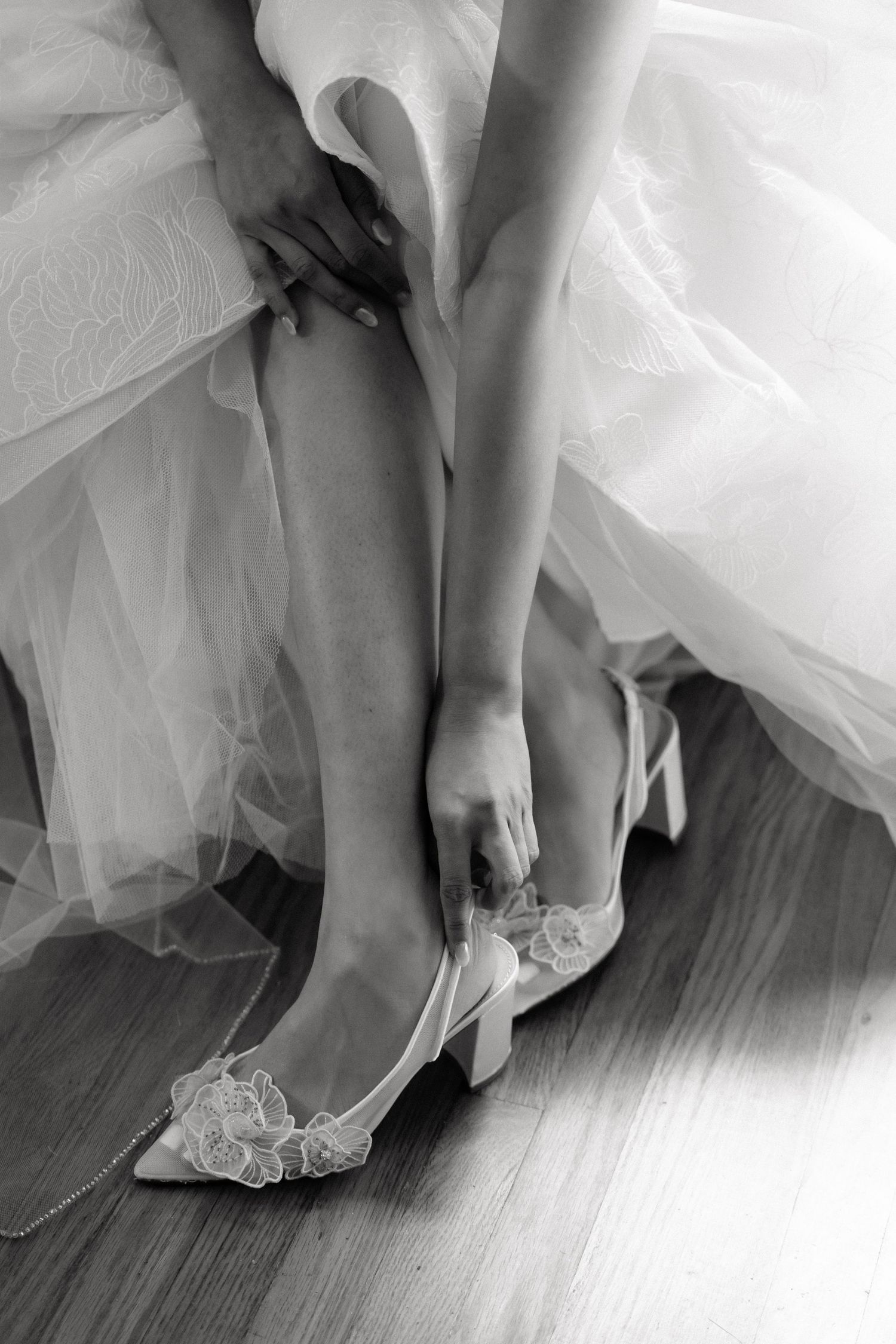 A sequence of black and white photos showing feet slipping into elegant bridal shoes on a hardwood floor.