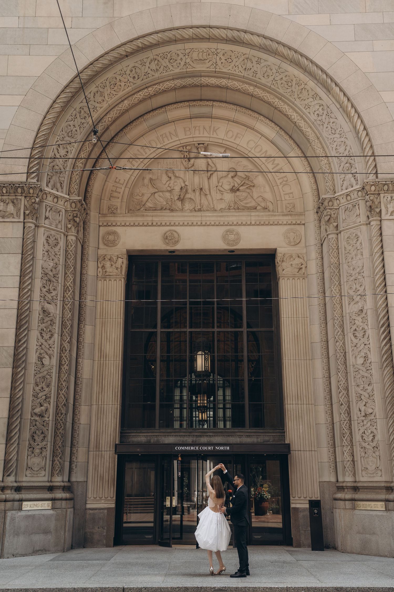People gather under ornate stone archways in a classical architectural setting capturing an elegant moment.