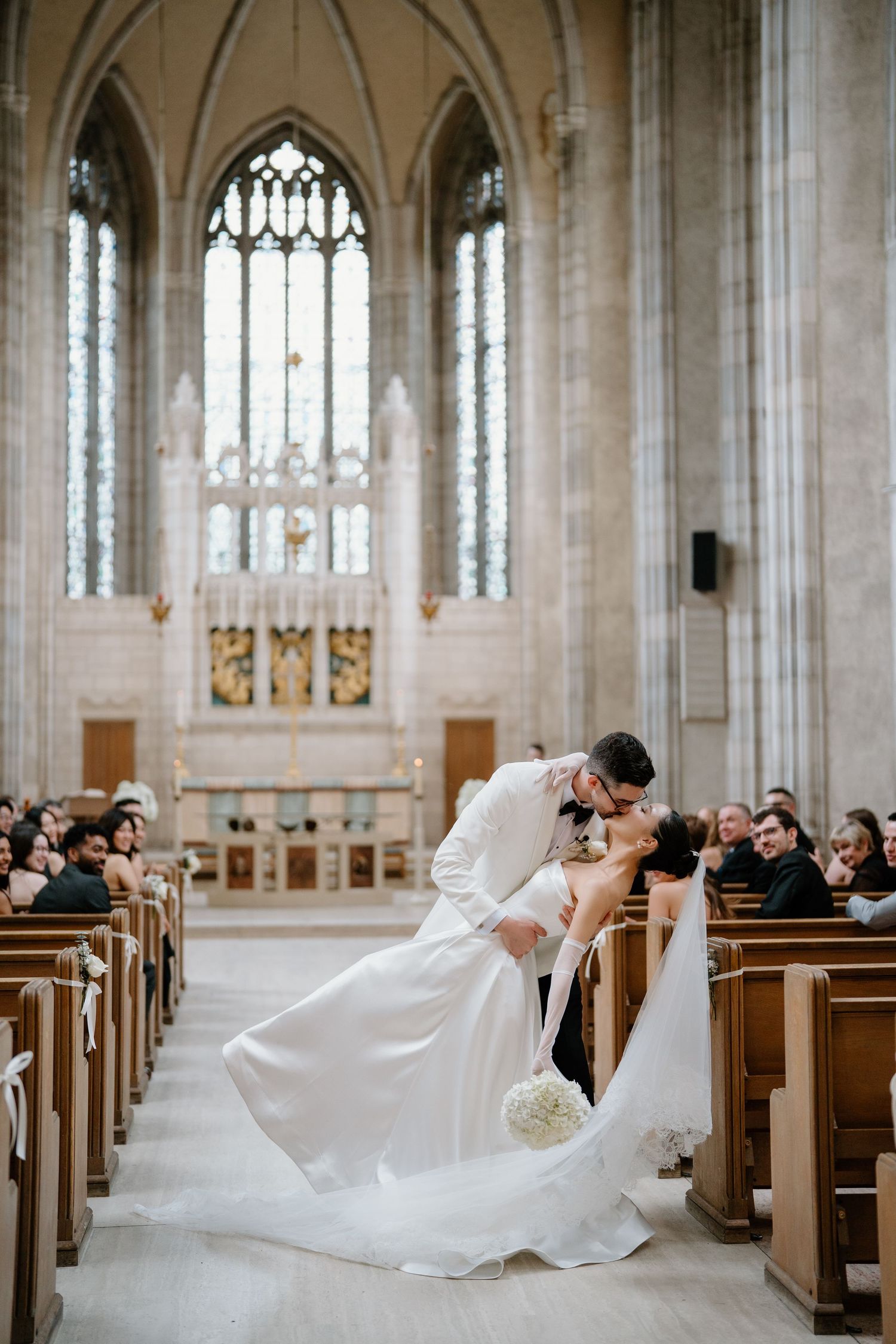Wedding couple creates artistic photo series in grand cathedral with wooden pews.