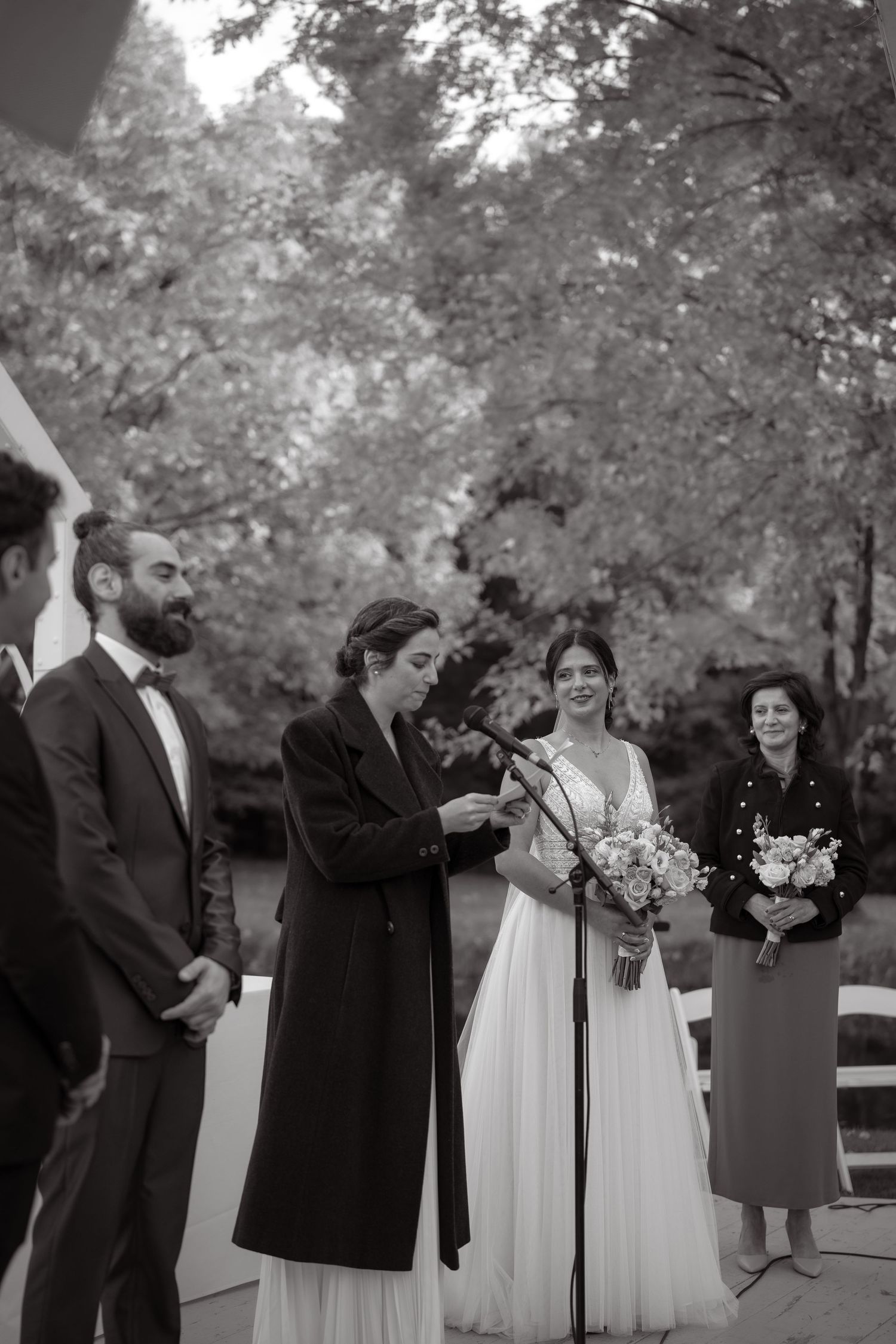 Black and white portrait of formal wedding ceremony with bouquet and formal attire.