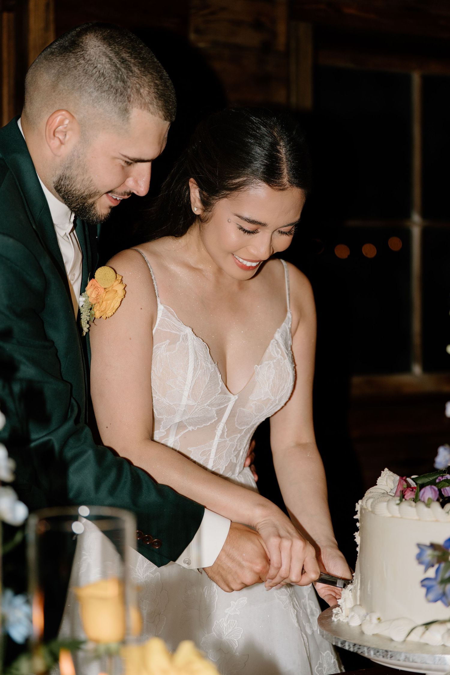 A couple cuts into their white wedding cake together during their reception celebration.