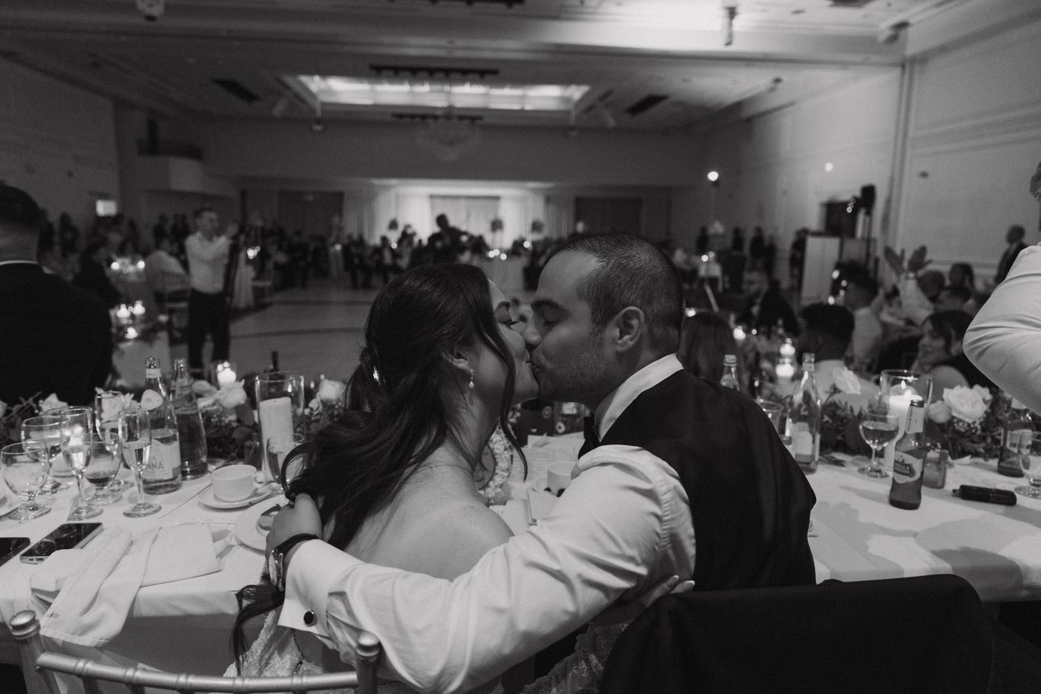 A black and white panoramic view of people seated at dining tables in a banquet hall during an event.
