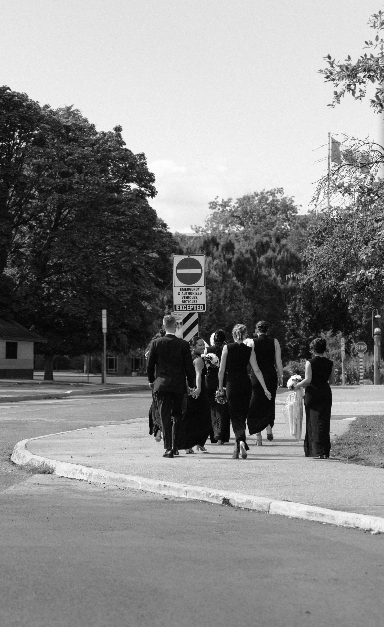 A group of graduates in black academic robes walking along a curved path on a college campus.
