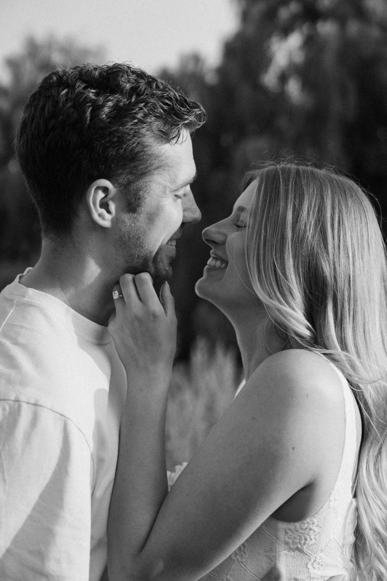 A tender moment captured in black and white as a couple shares a romantic kiss outdoors.