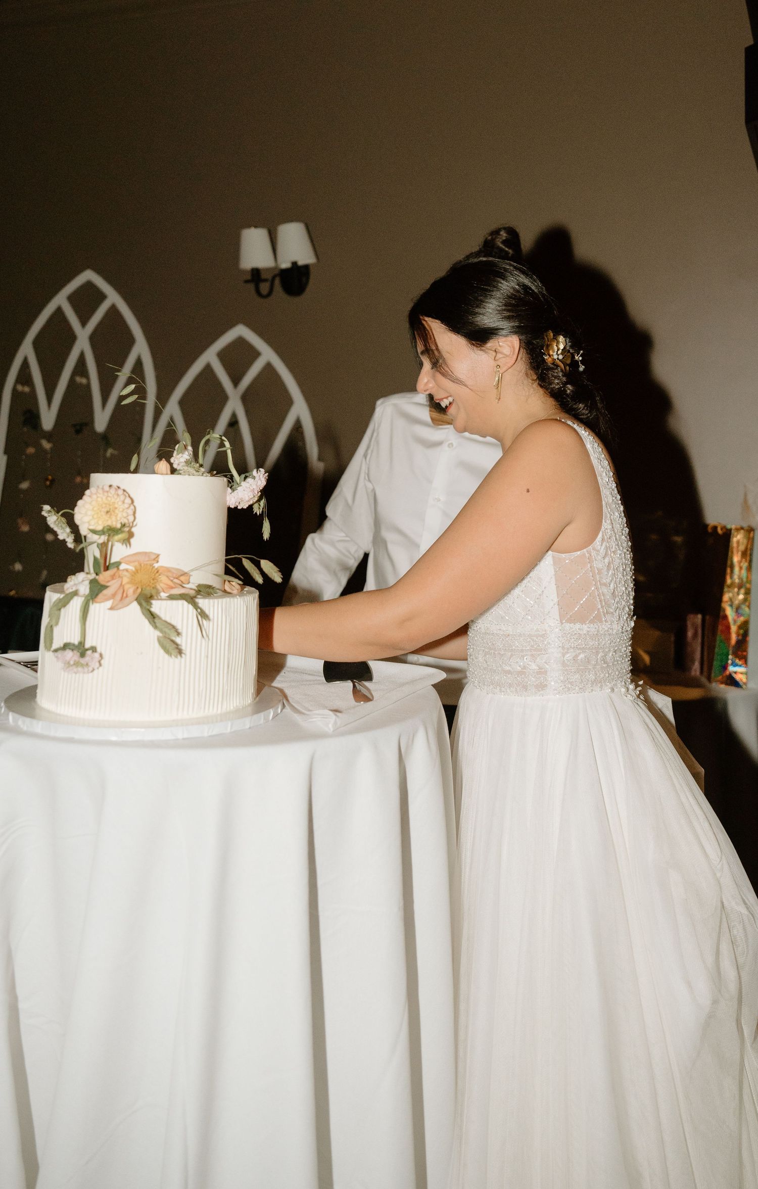 A bride in a white gown prepares to cut the elegant two-tiered wedding cake.