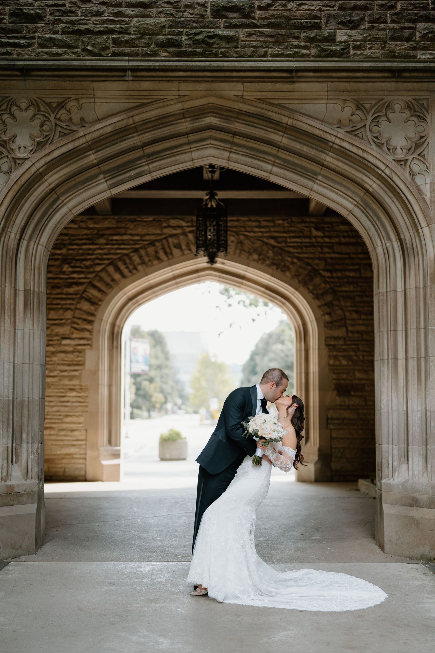 Wedding couple shares romantic moments under a series of Gothic stone archways.