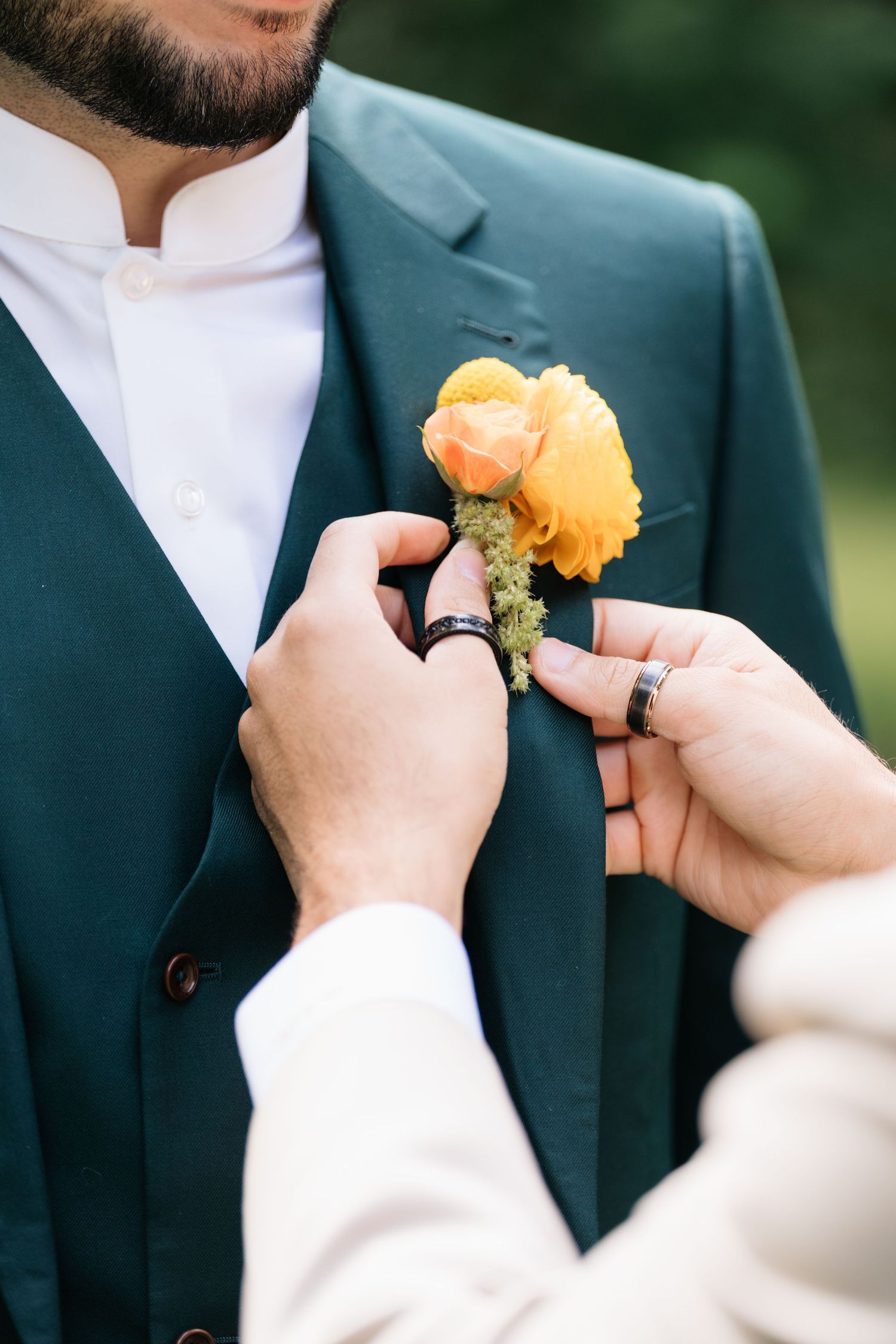 Close-up shots of hands pinning yellow boutonnières onto formal suit jackets during wedding preparations.
