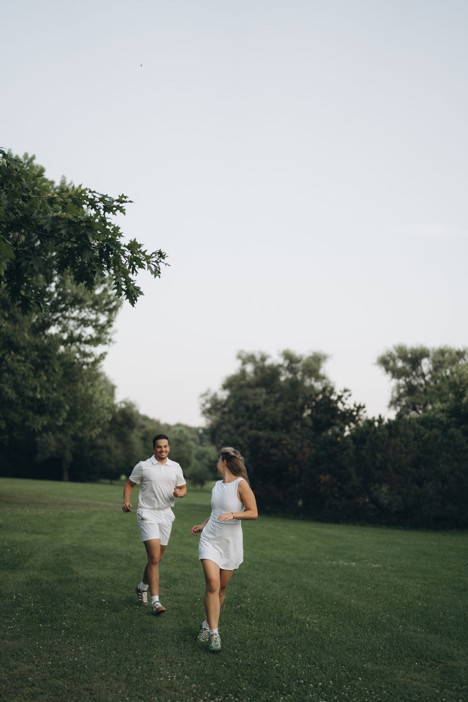 Two people strolling together across a grassy hillside on a sunny afternoon.