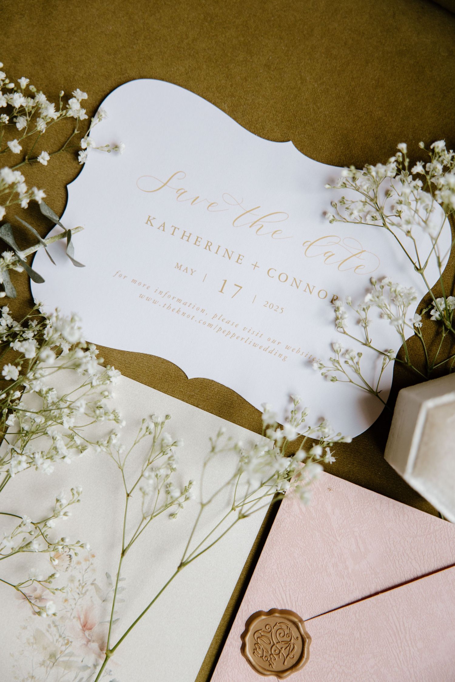Elegant wedding invitations in white and pink with wax seals and delicate baby's breath floral accents.