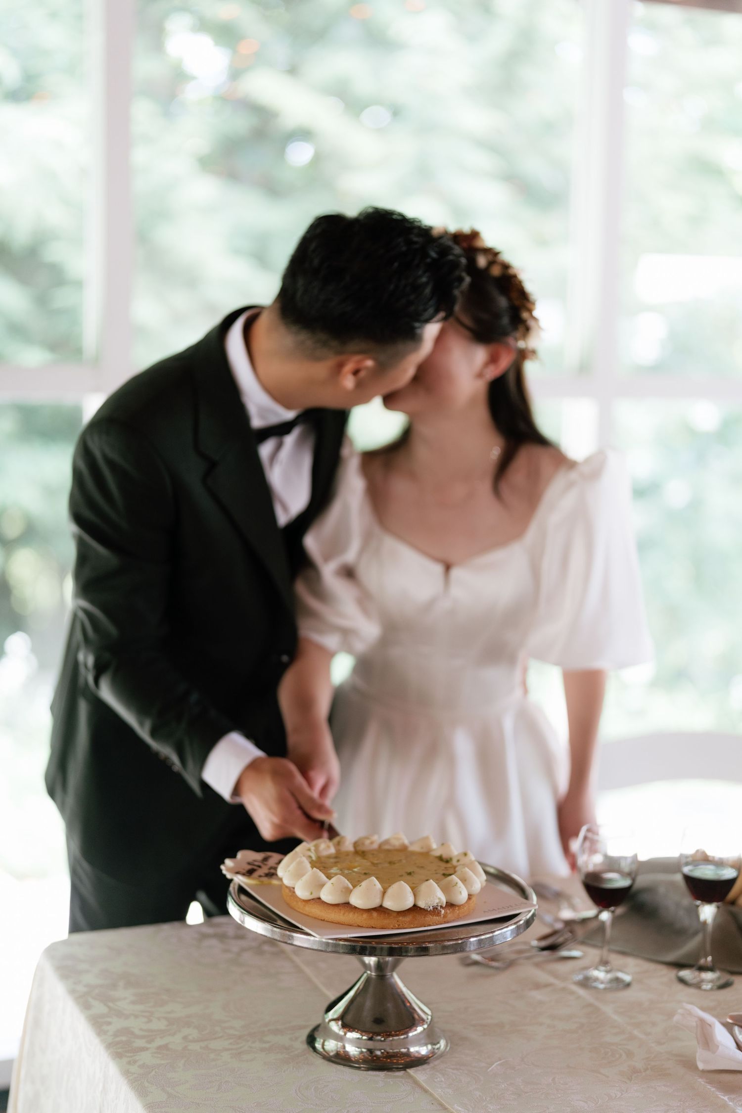 Bride and groom kissing while cutting their wedding cake, professional Toronto wedding photography by AZ Photo Studio
