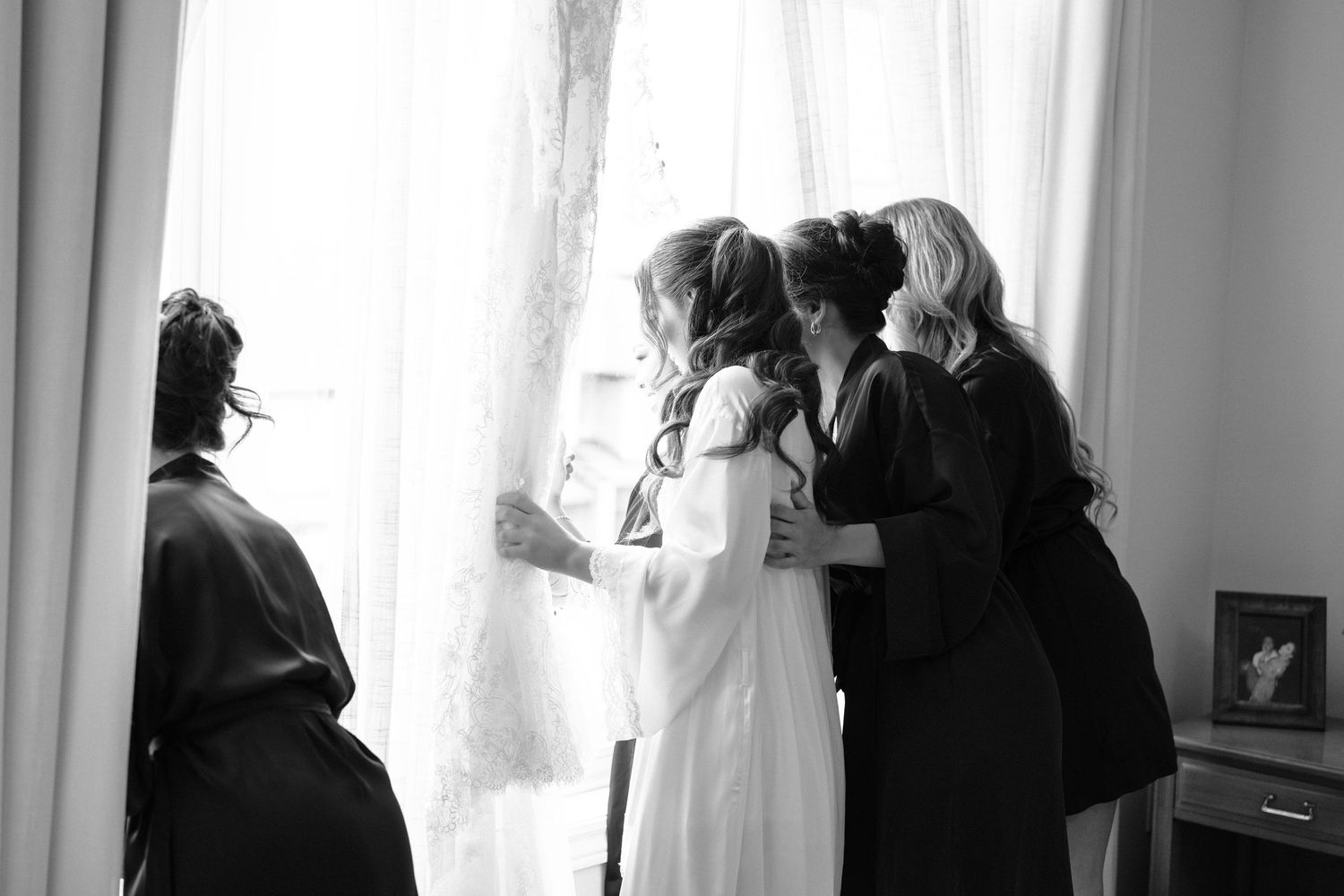 A black and white silhouette of a person in profile against a bright window with curtains.
