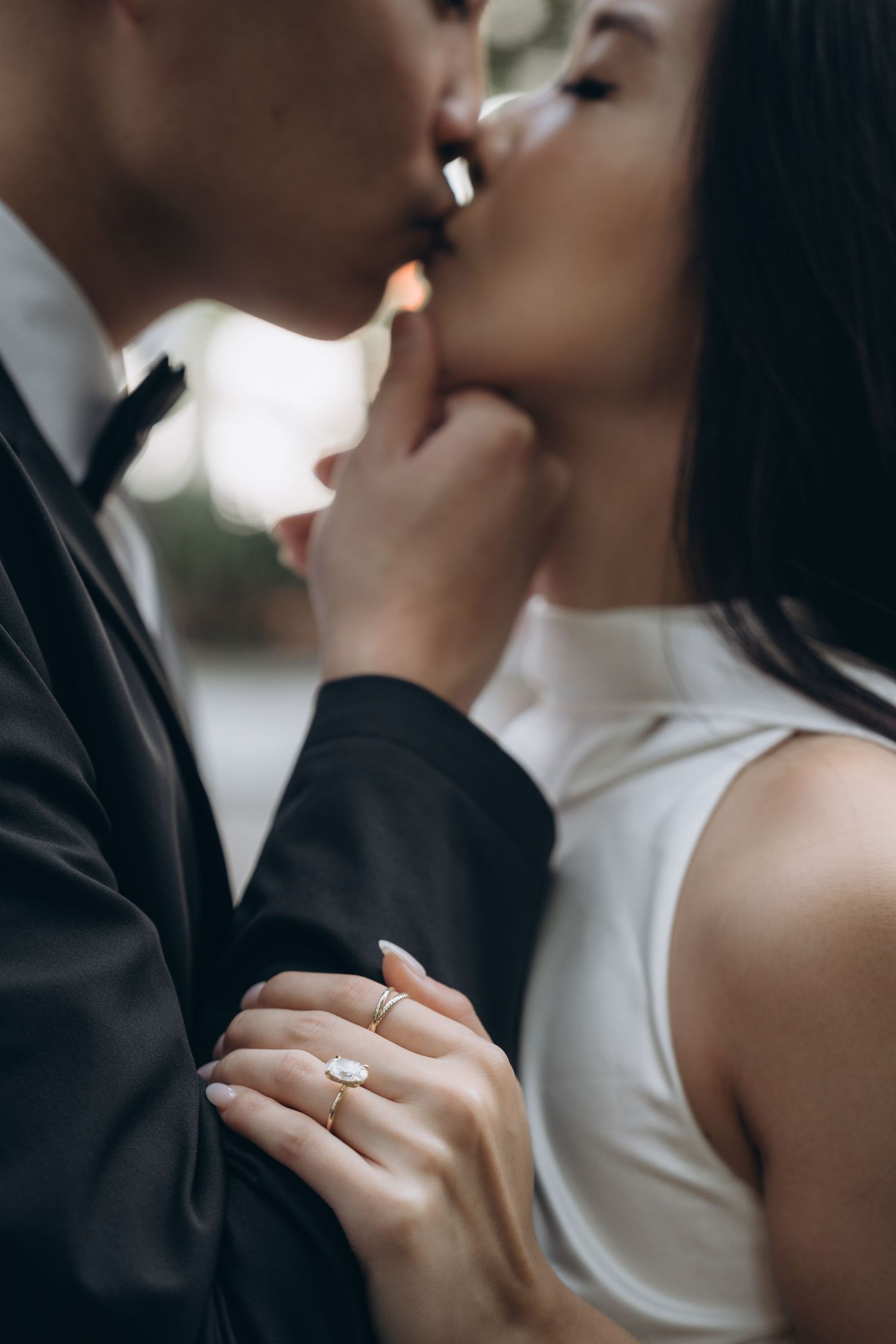 Close up of an engaged couple sharing an intimate moment, with the bride's diamond ring visible.